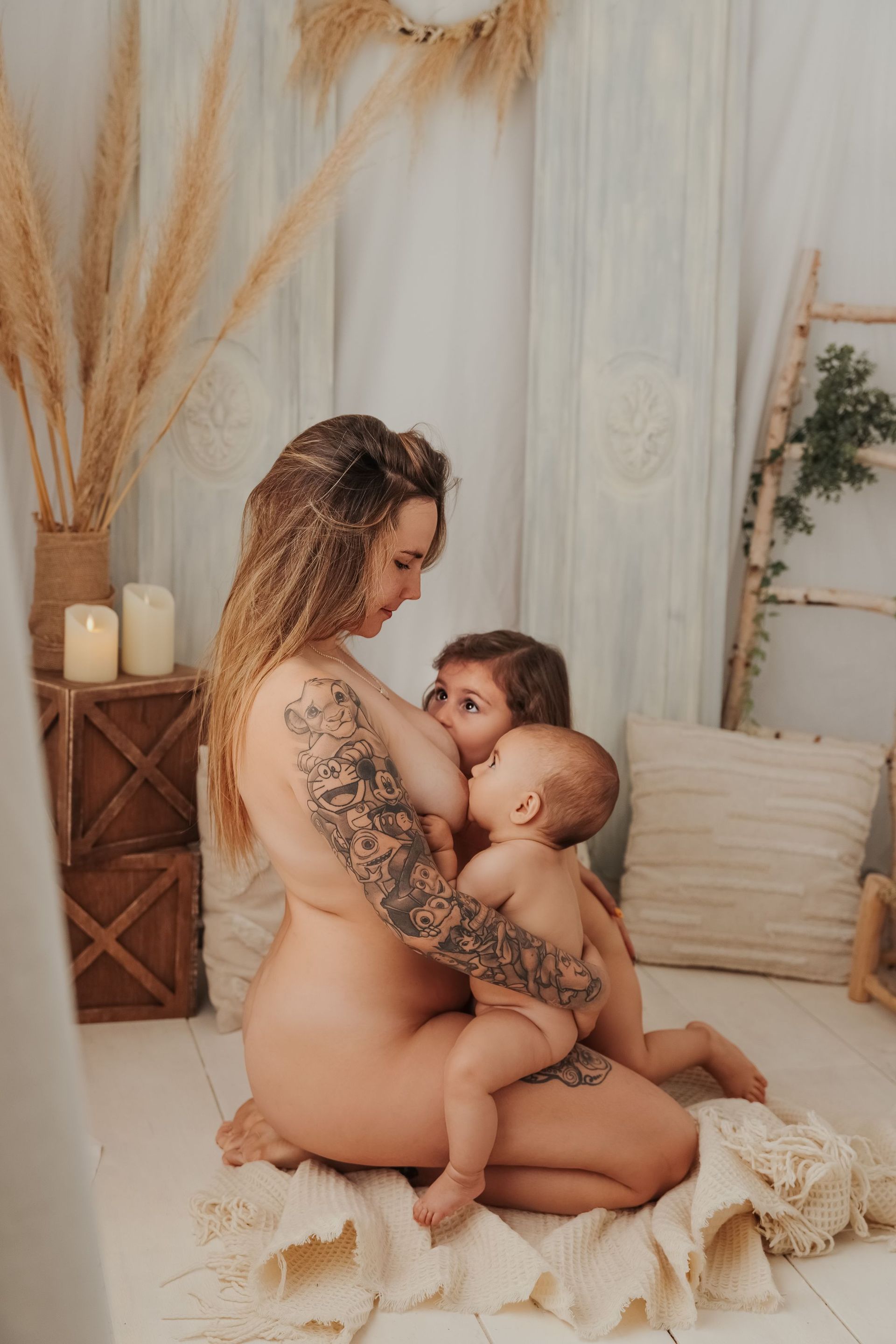 Un padre acuna a su bebé sobre una manta color crema en una habitación infantil de estilo bohemio con iluminación tenue.