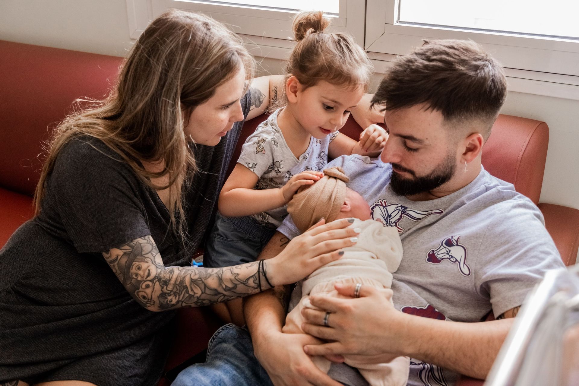 Una familia acuna a un recién nacido en un sofá; dos adultos y un niño están muy cerca.