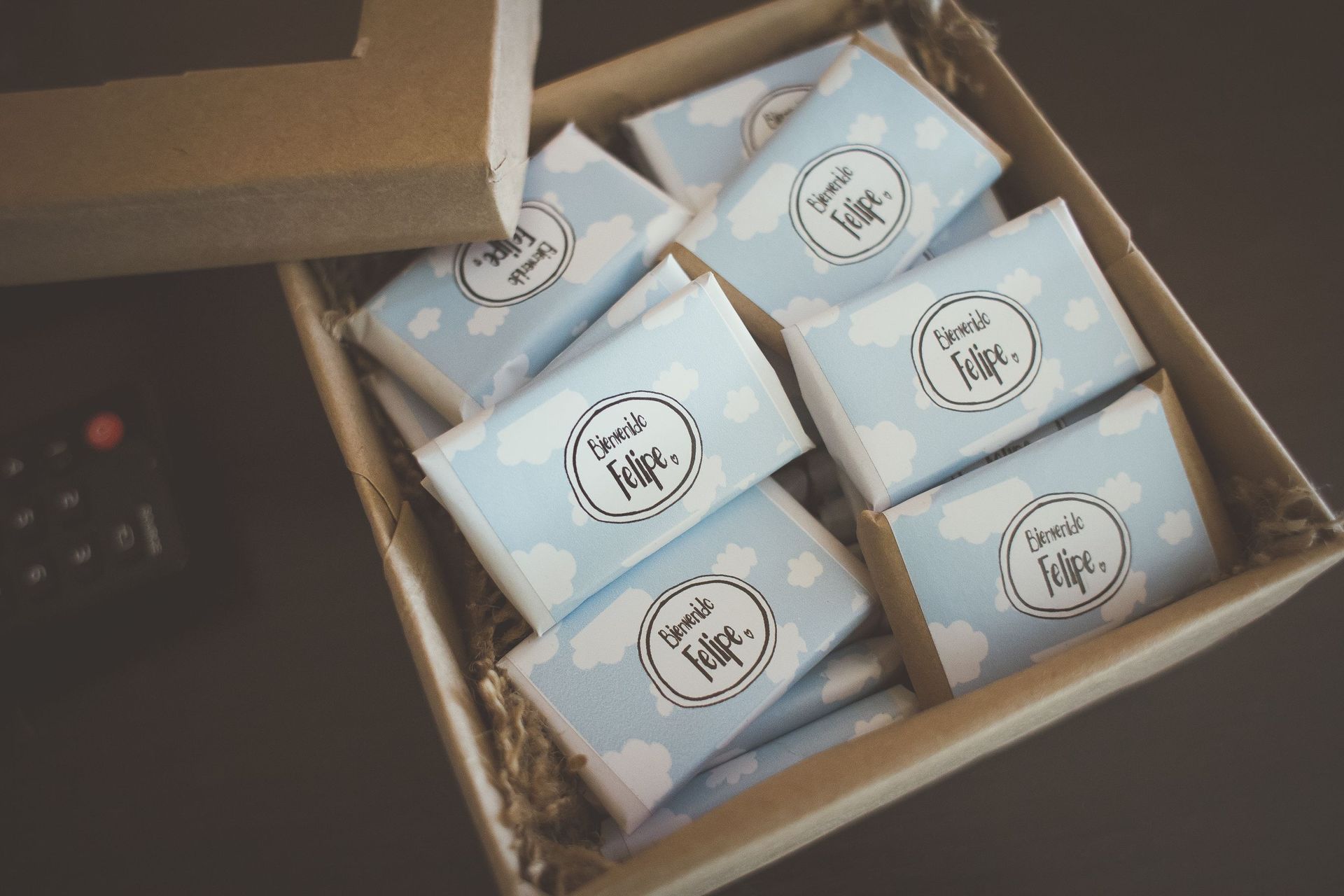 Caja abierta que contiene seis cajas de regalo envueltas en papel azul y blanco con etiquetas circulares.