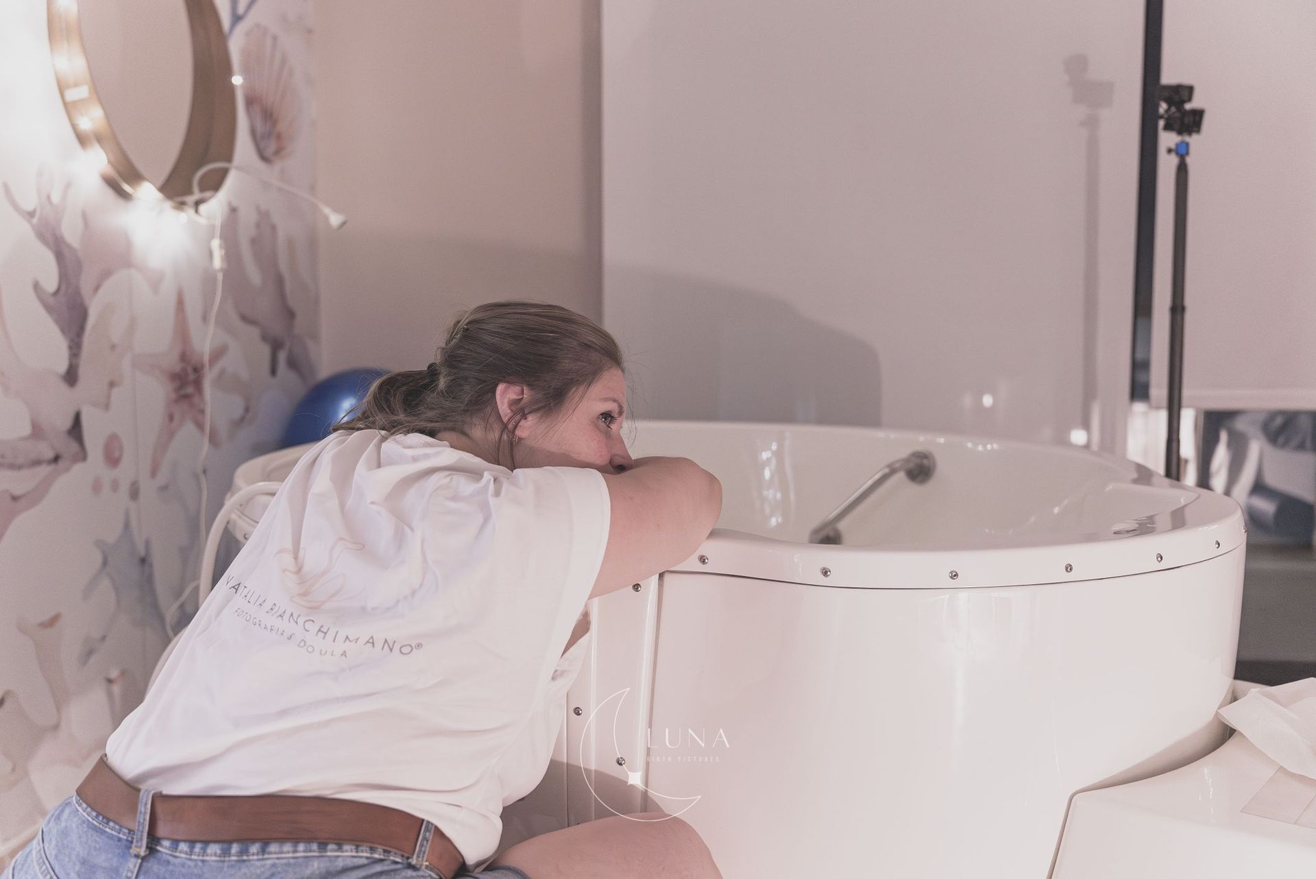 Persona inclinada sobre una bañera blanca, lavándose o enjuagándose el pelo en un baño.