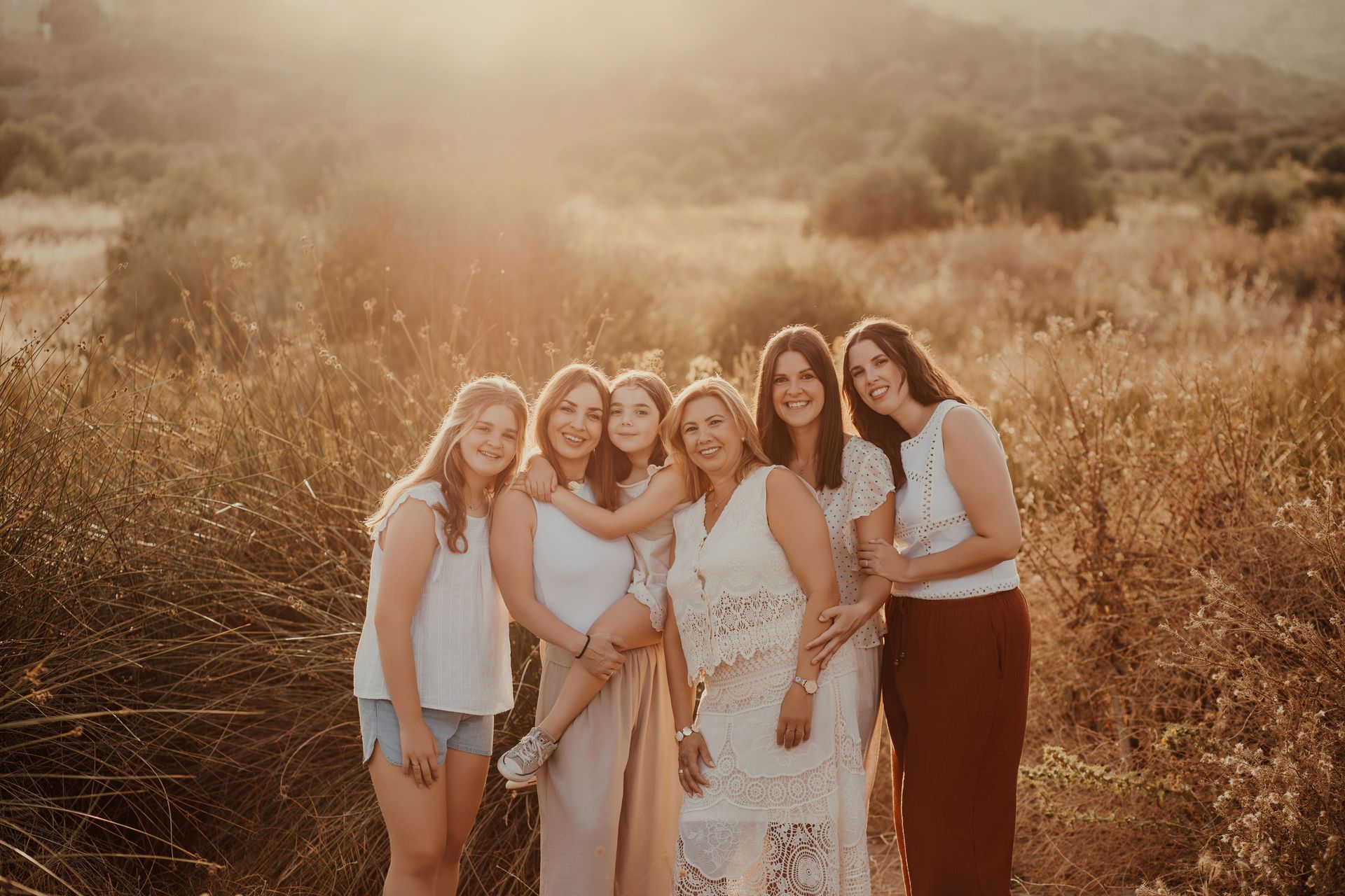 Seis mujeres de pie juntas en un campo soleado, sonriendo a la cámara.
