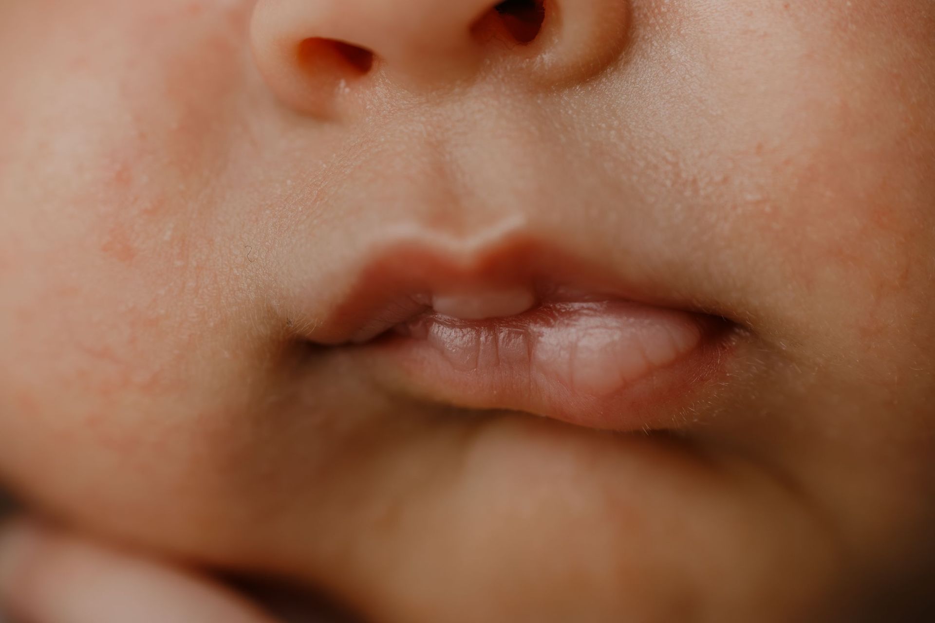 Primer plano de la nariz, las mejillas y los labios ligeramente entreabiertos de un bebé.