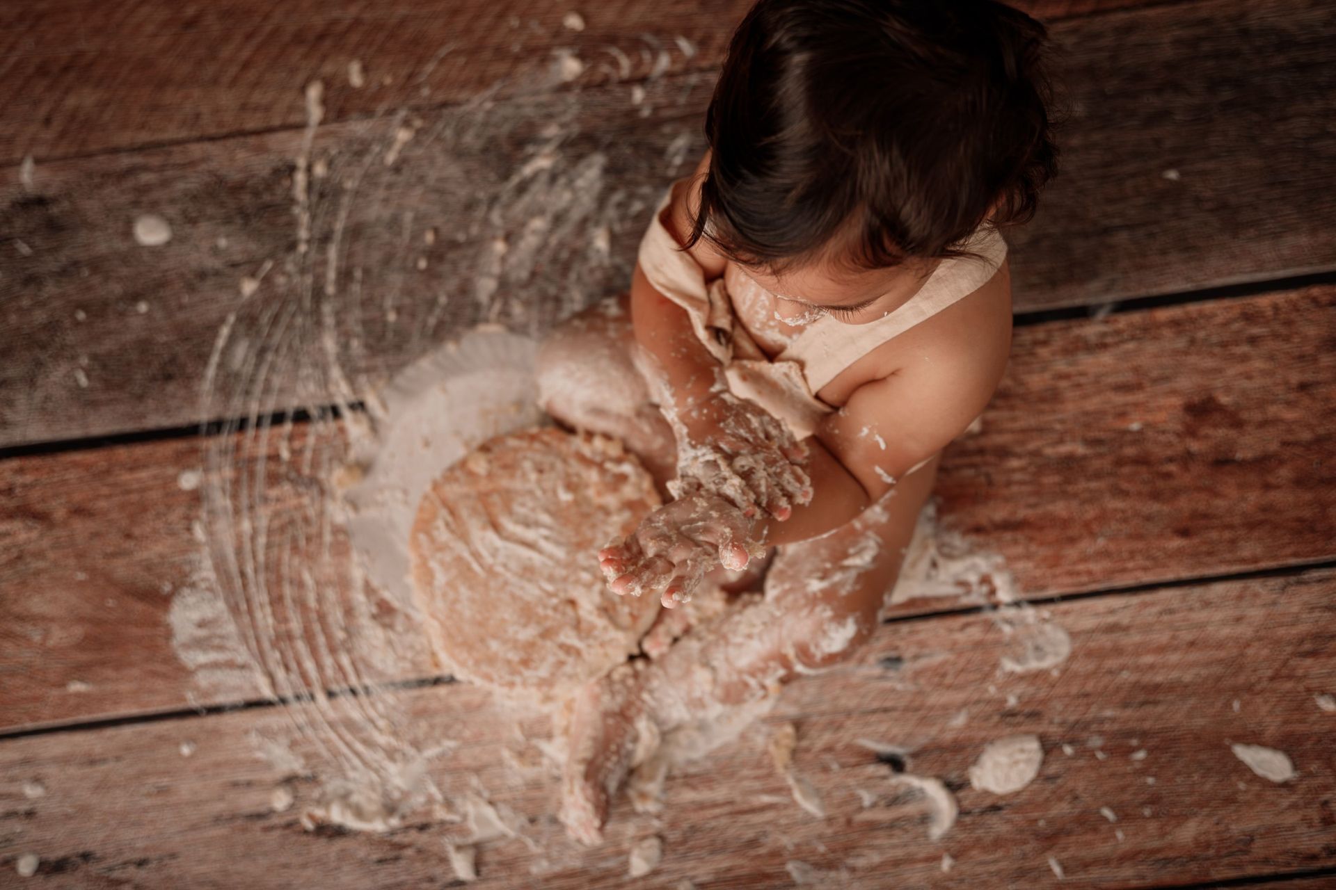 Un niño pequeño jugando con agua y burbujas en un suelo de madera.