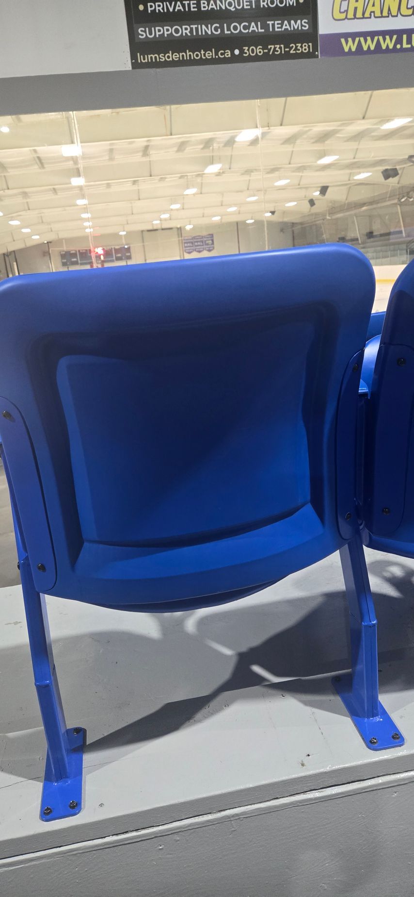 A row of blue chairs are lined up in a stadium.