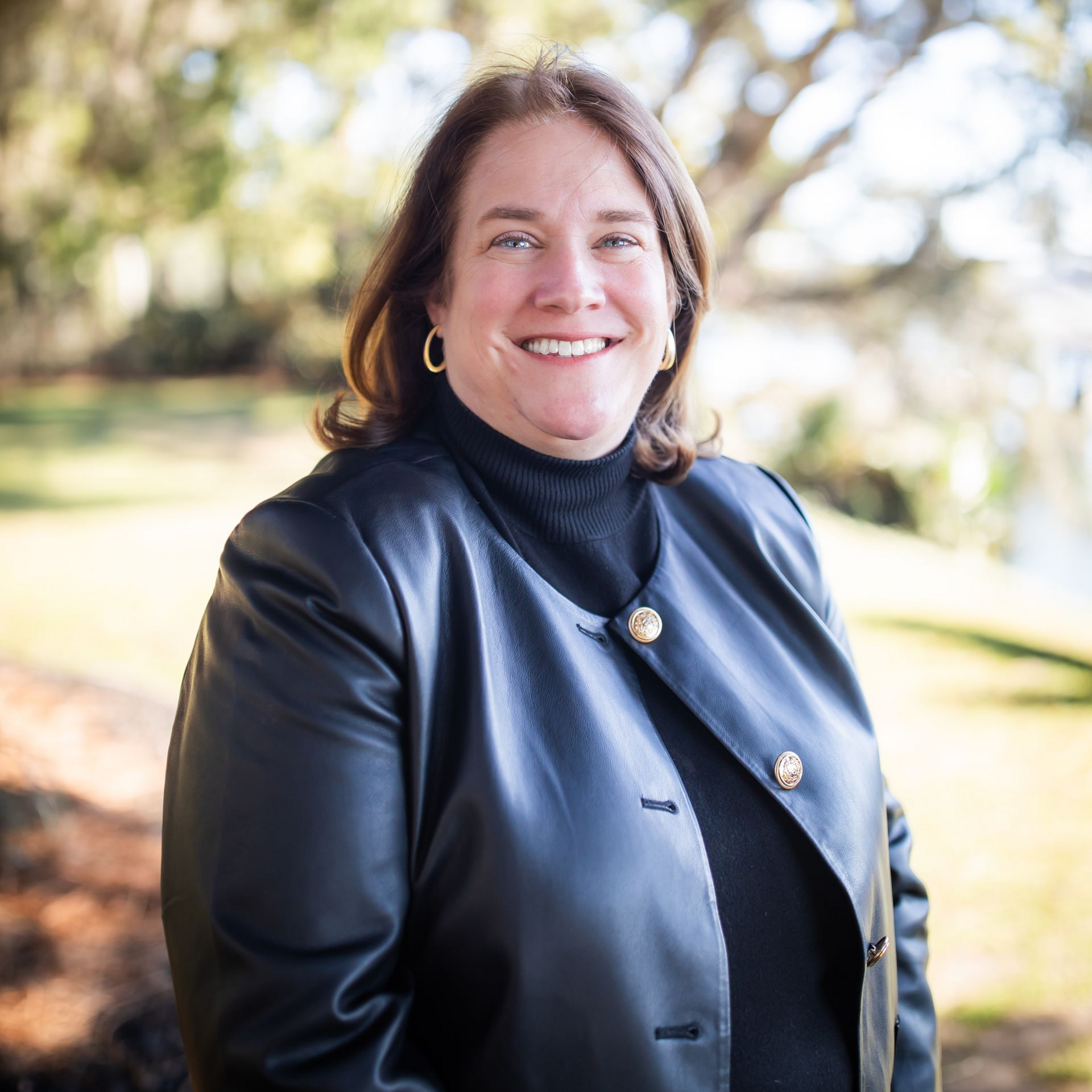 A woman in a black jacket is smiling for the camera.