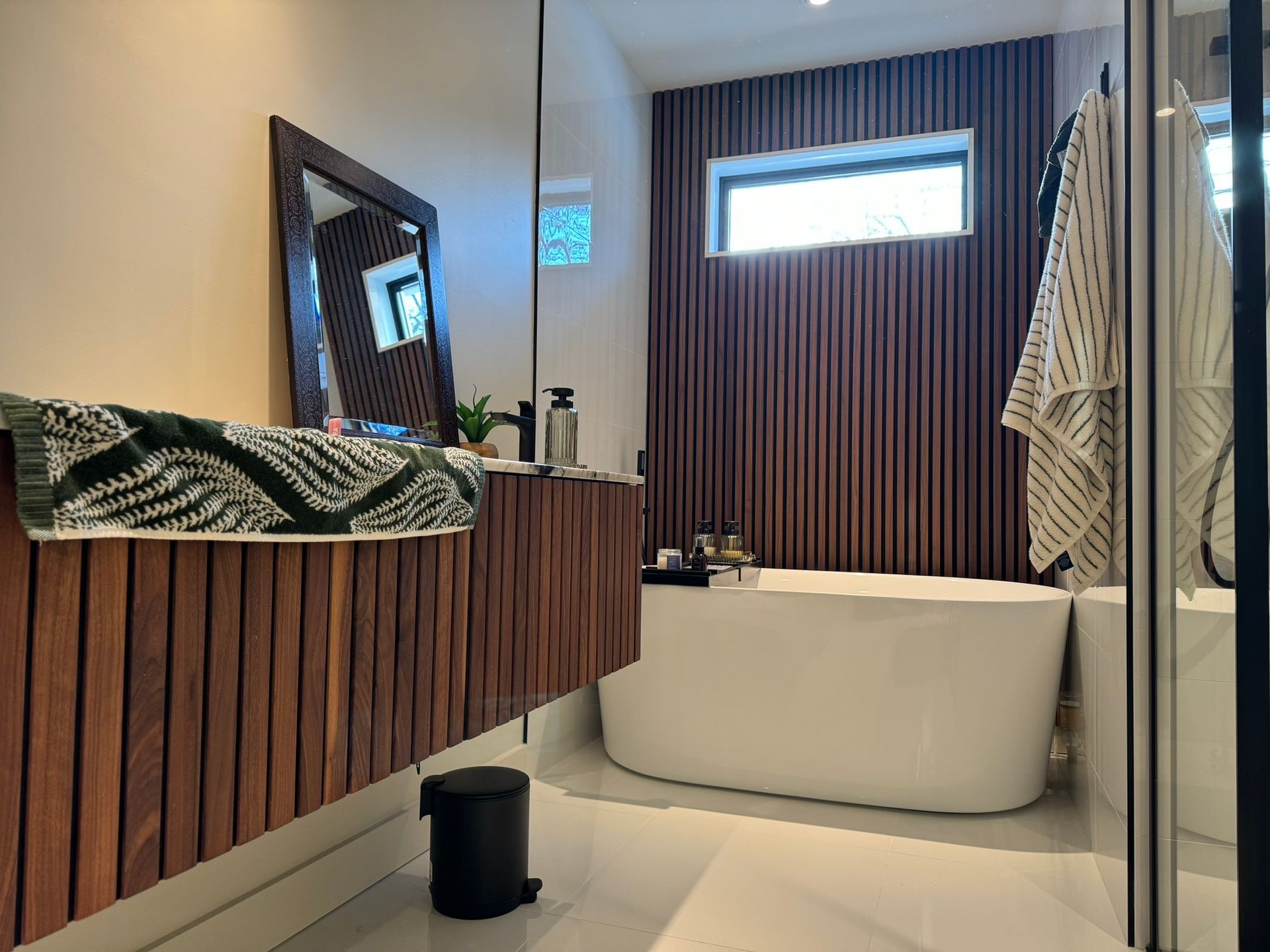 Salle de bains moderne avec lambris, baignoire et meuble-lavabo suspendu.