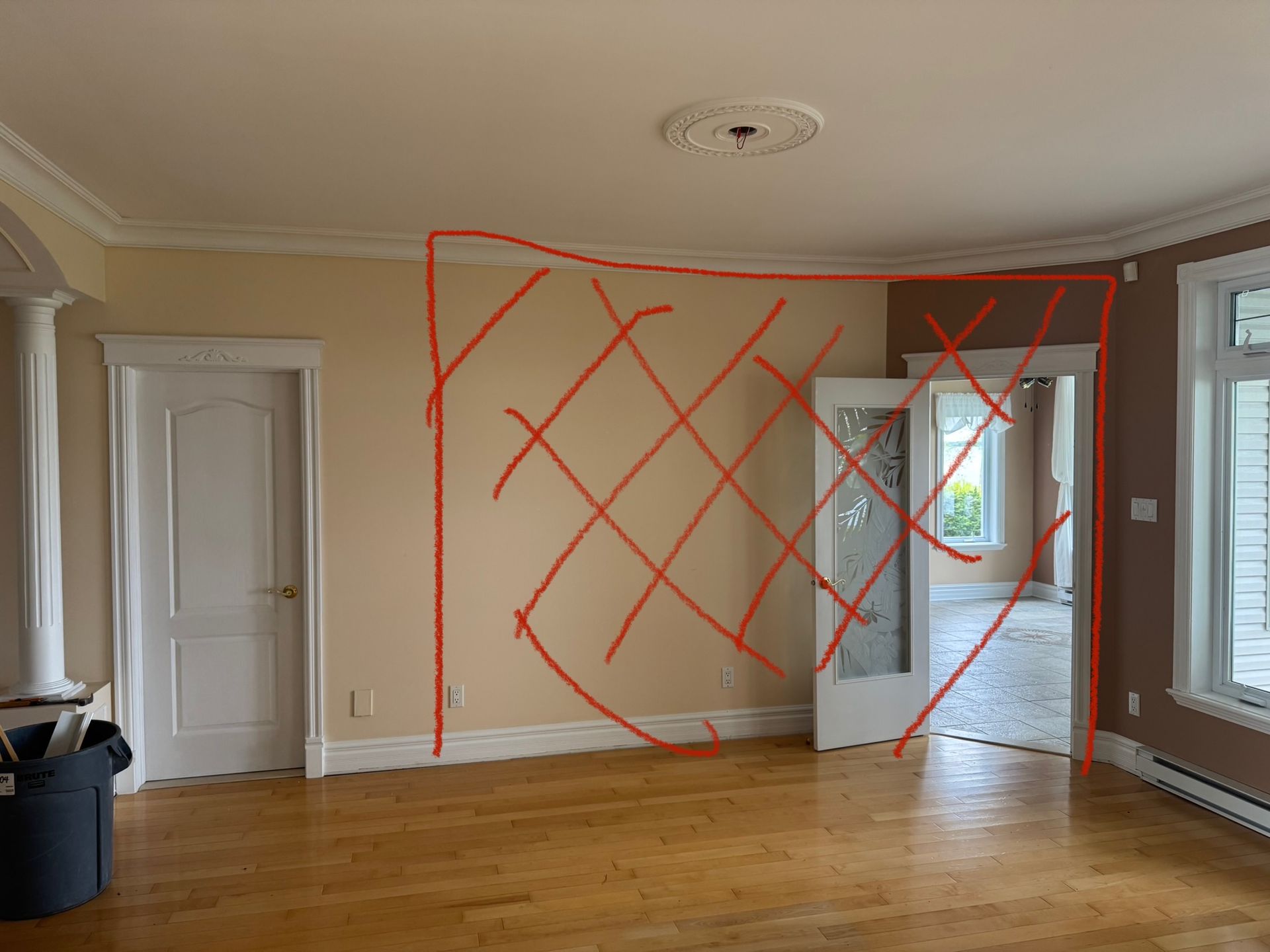 Salon avec parquet, une porte et un mur orné d'un schéma rouge.