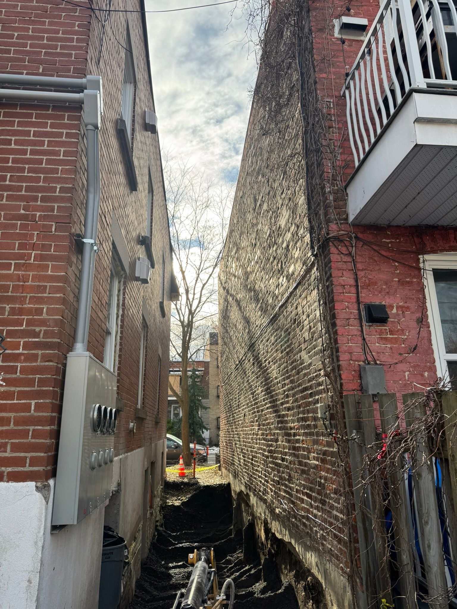 Ruelle étroite entre deux immeubles en briques. On aperçoit une gaine électrique et un balcon.