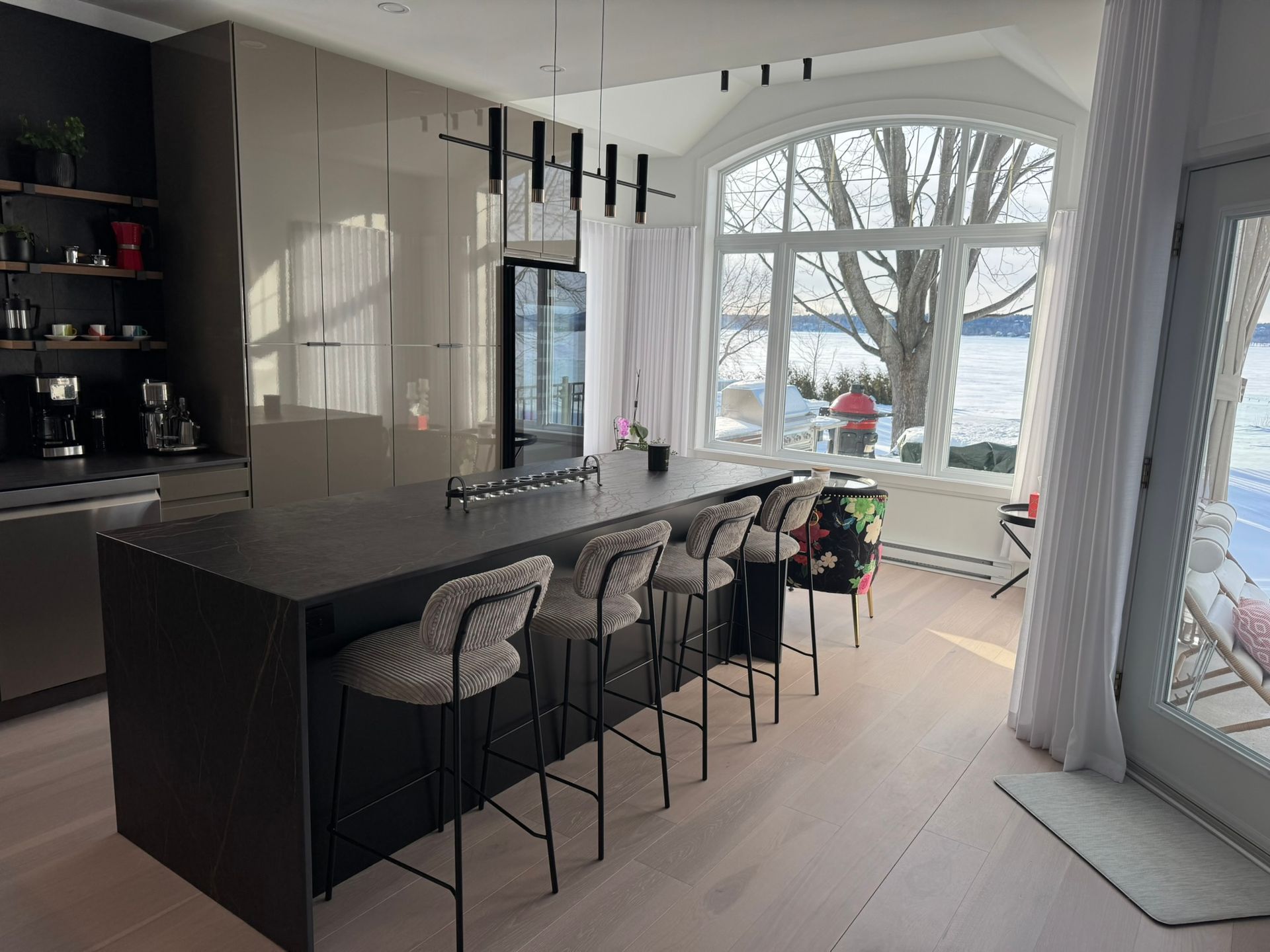 Cuisine moderne avec îlot central, coin repas et fenêtre donnant sur le lac.