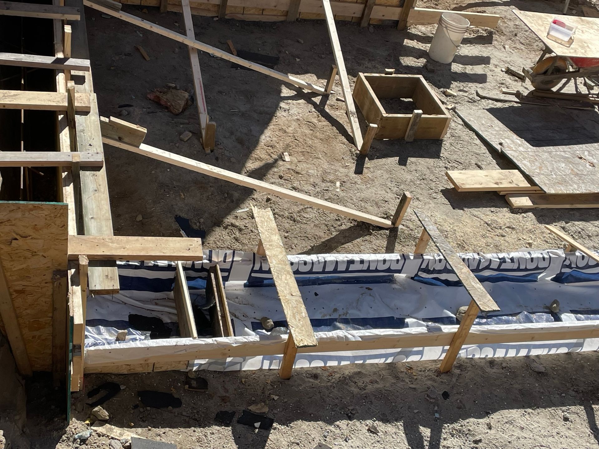 Coffrages en bois pour la construction de fondations en béton, avec poutres de soutien et isolation.