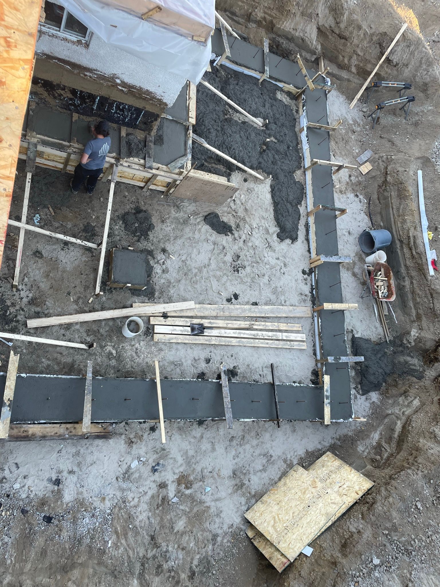 Chantier de construction en cours de remplissage de coffrages en béton. Un ouvrier se tient à l'intérieur.