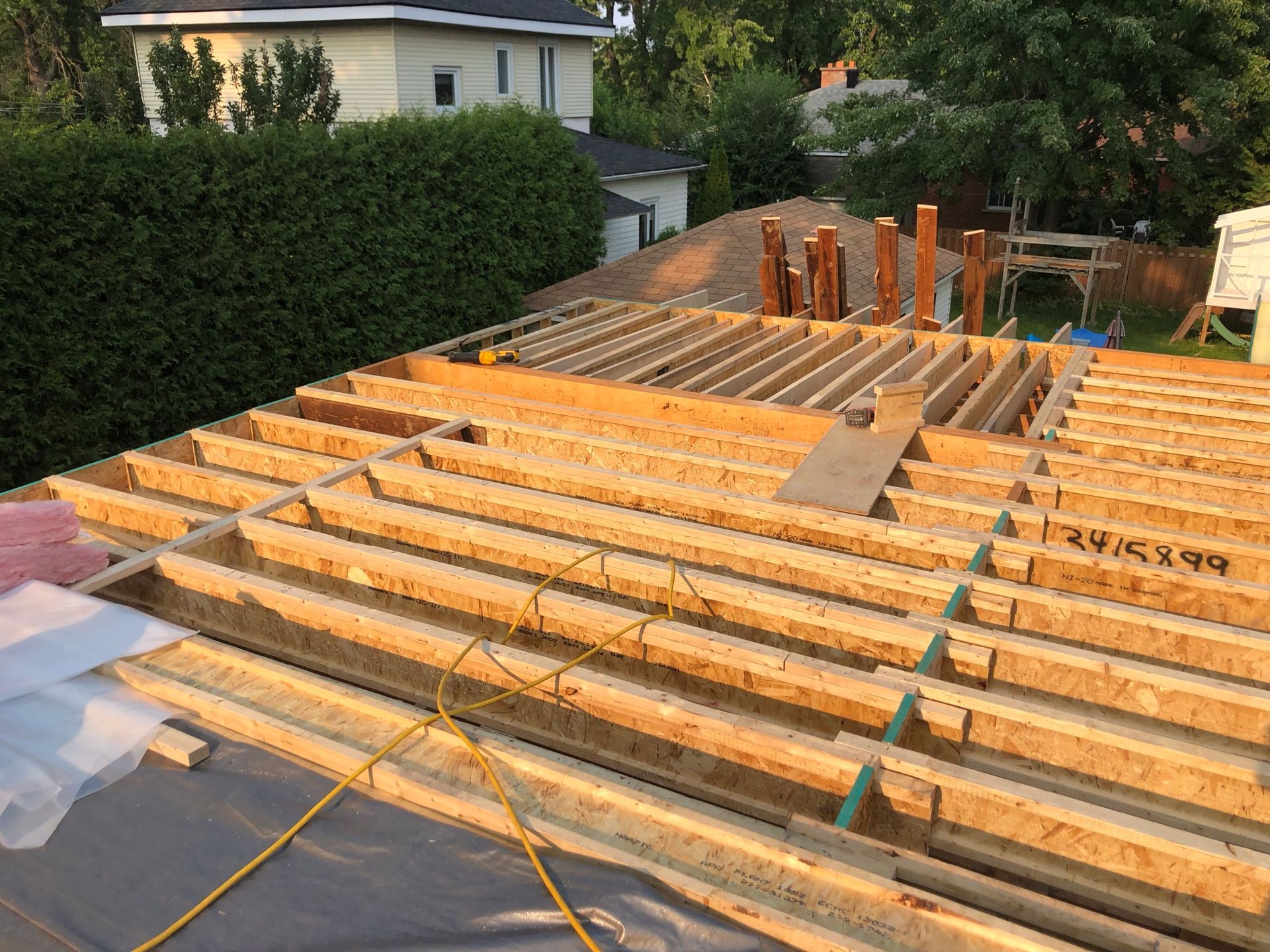 Toiture en construction, poutres et charpente en bois visibles.