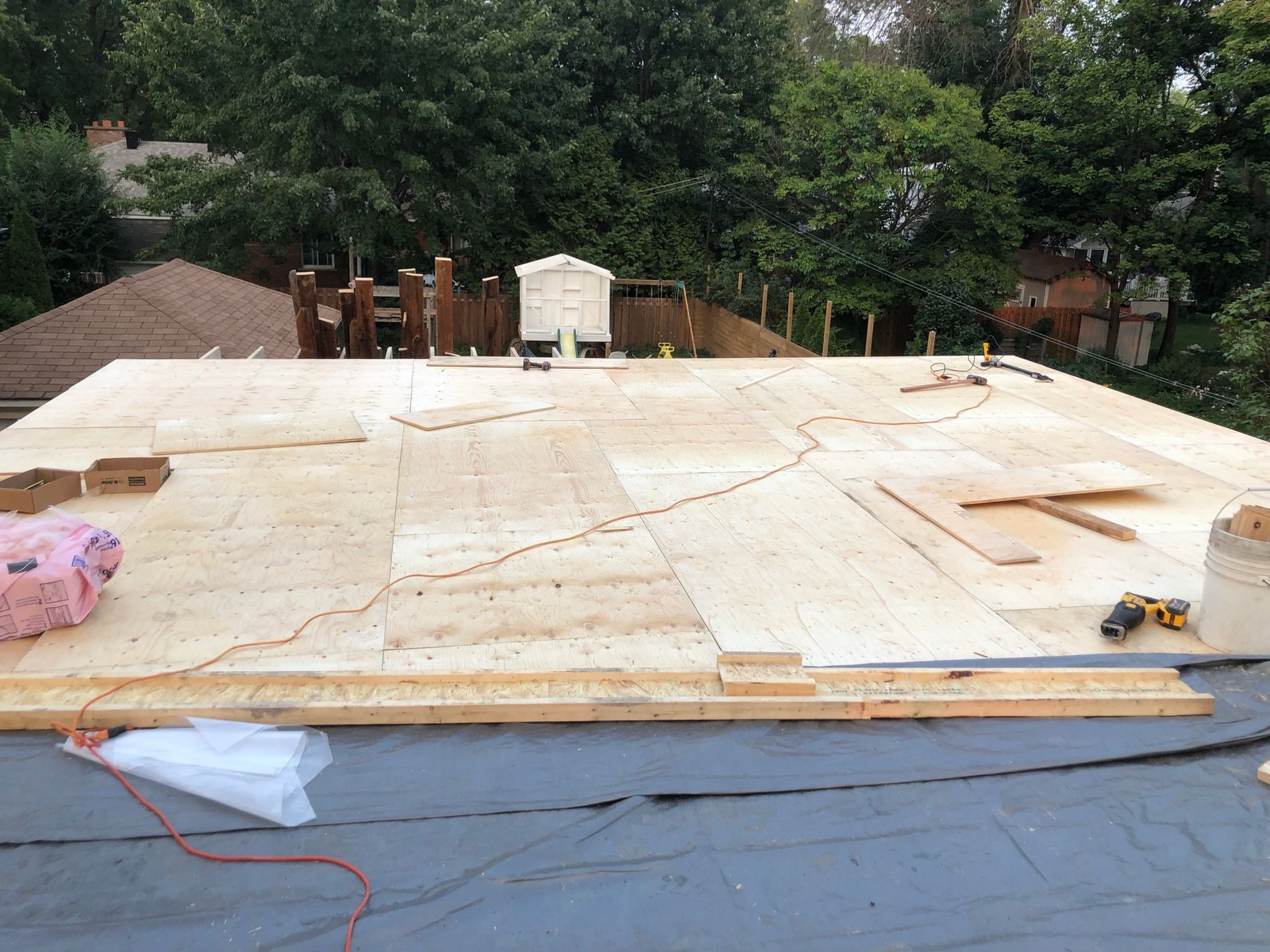 Toiture en construction : panneaux de contreplaqué, outils et matériaux sont étalés sur toute la surface.