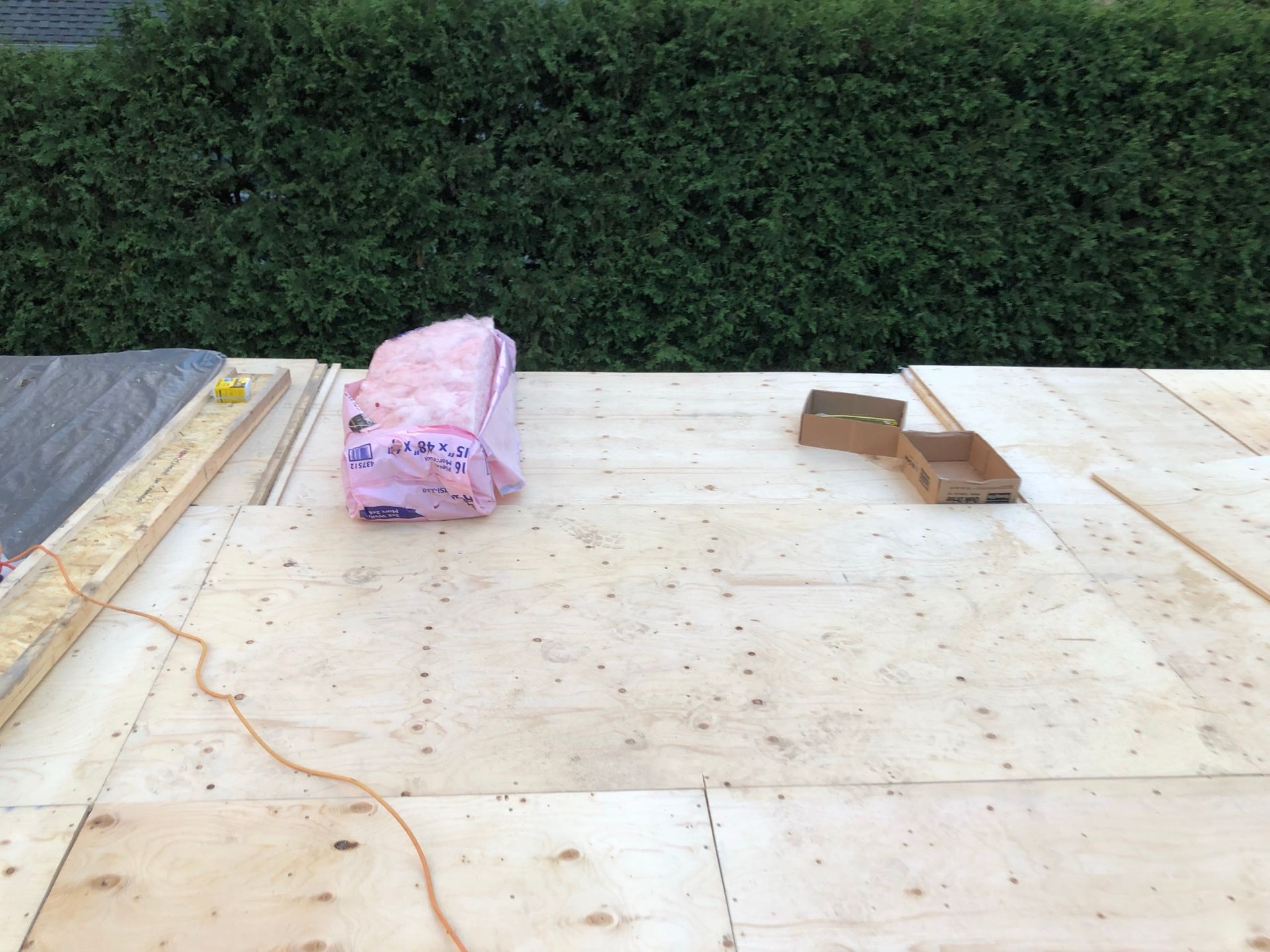 Construction d'un toit en bois avec isolation, carton et outils.