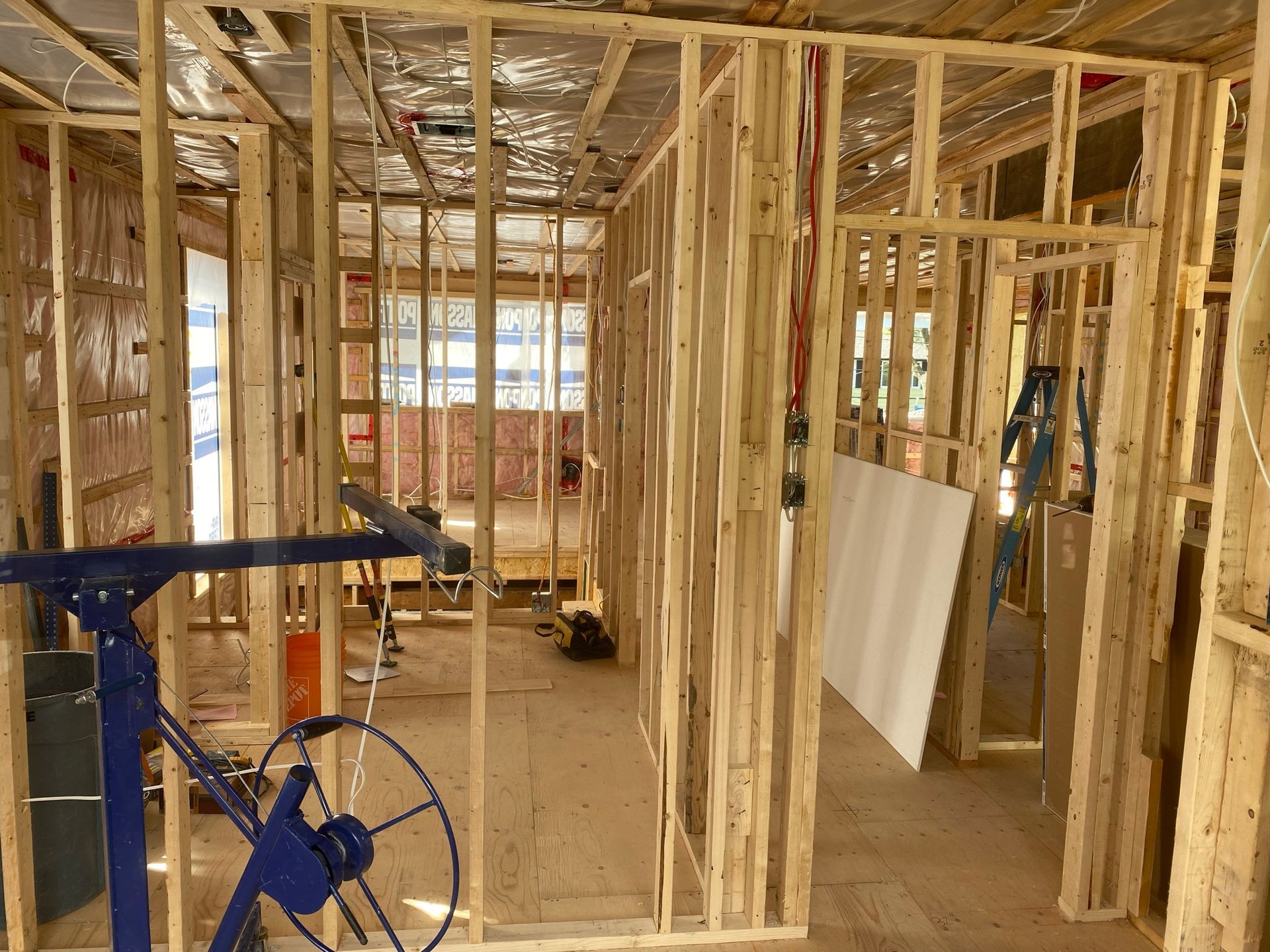 Ossature bois intérieure d'une maison en construction ; murs non finis, encadrement de porte et levage de cloisons sèches.
