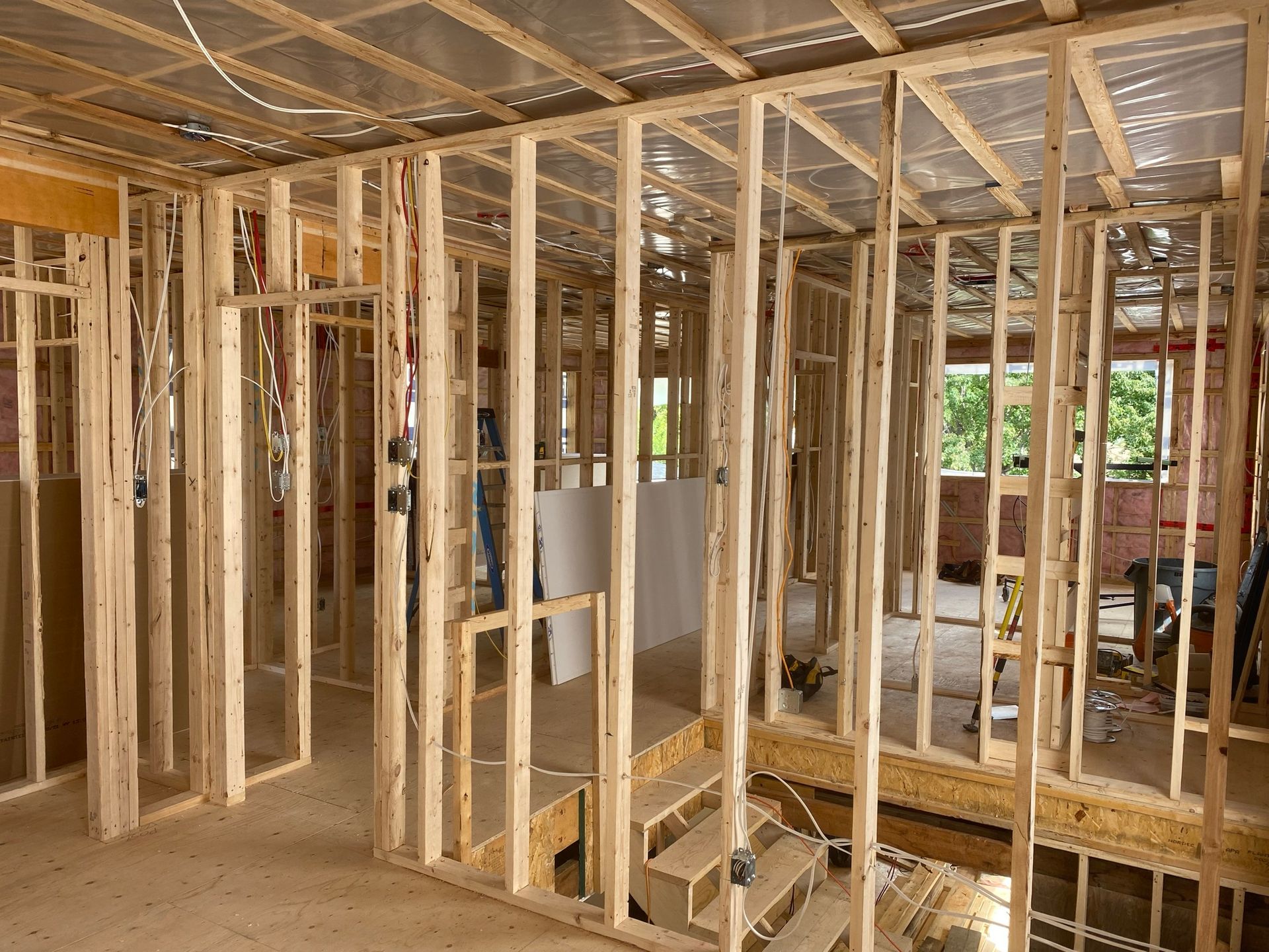 Vue intérieure d'un bâtiment en construction, montrant la charpente en bois et la cage d'escalier.