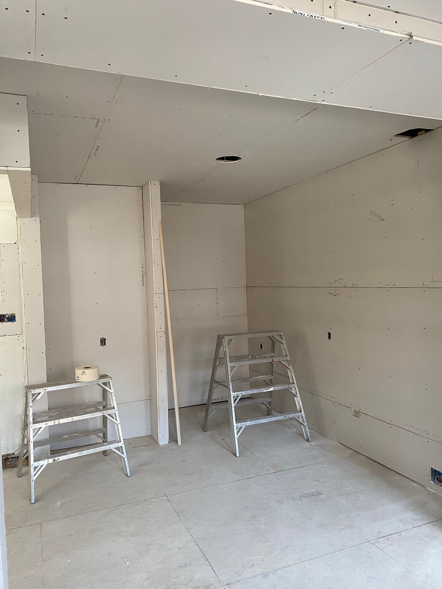 Pièce intérieure en cours de construction avec cloisons sèches et échelles.