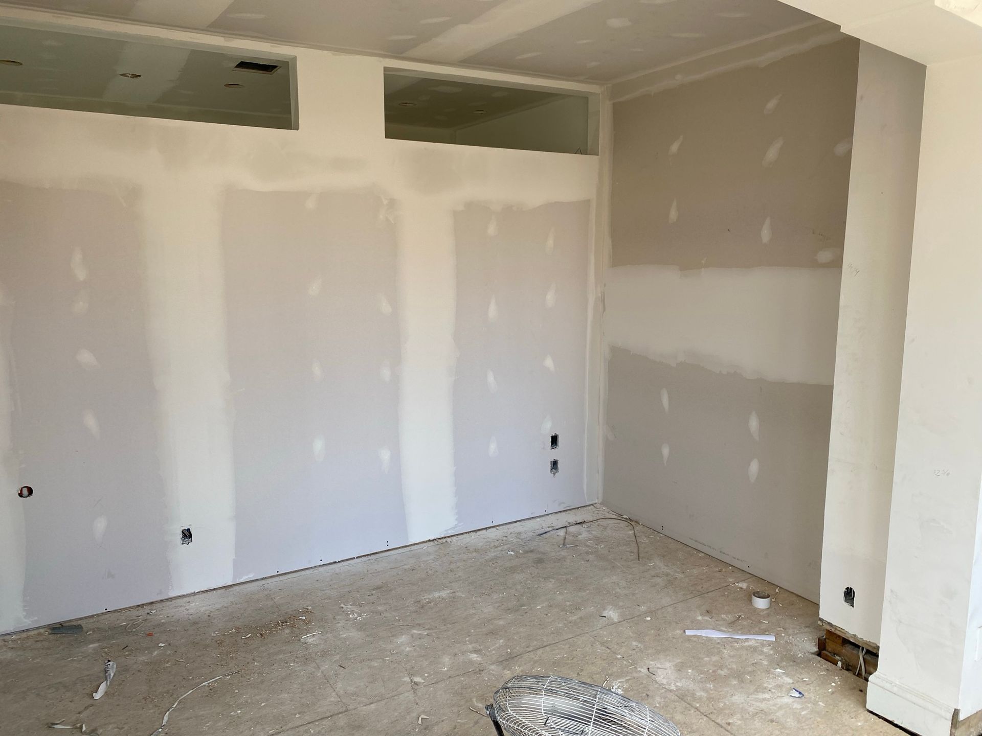 Pièce intérieure en cours d'aménagement, avec cloisons sèches installées aux murs et au plafond, sol non fini.