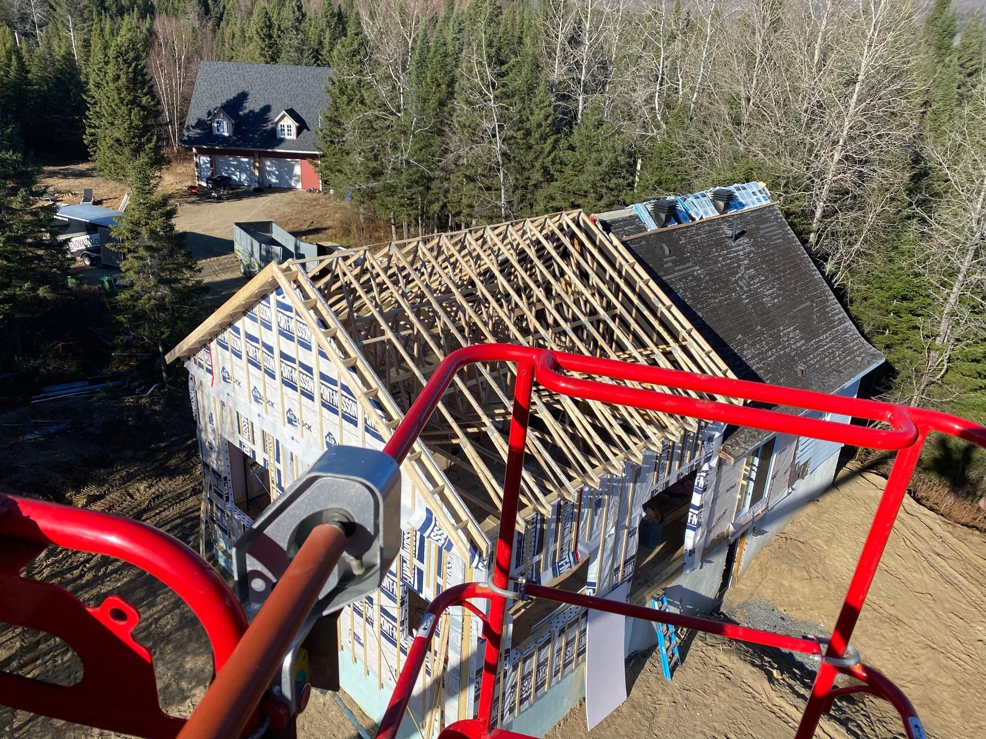 Maison en construction avec charpente apparente et toiture partielle ; vue depuis l'ascenseur.