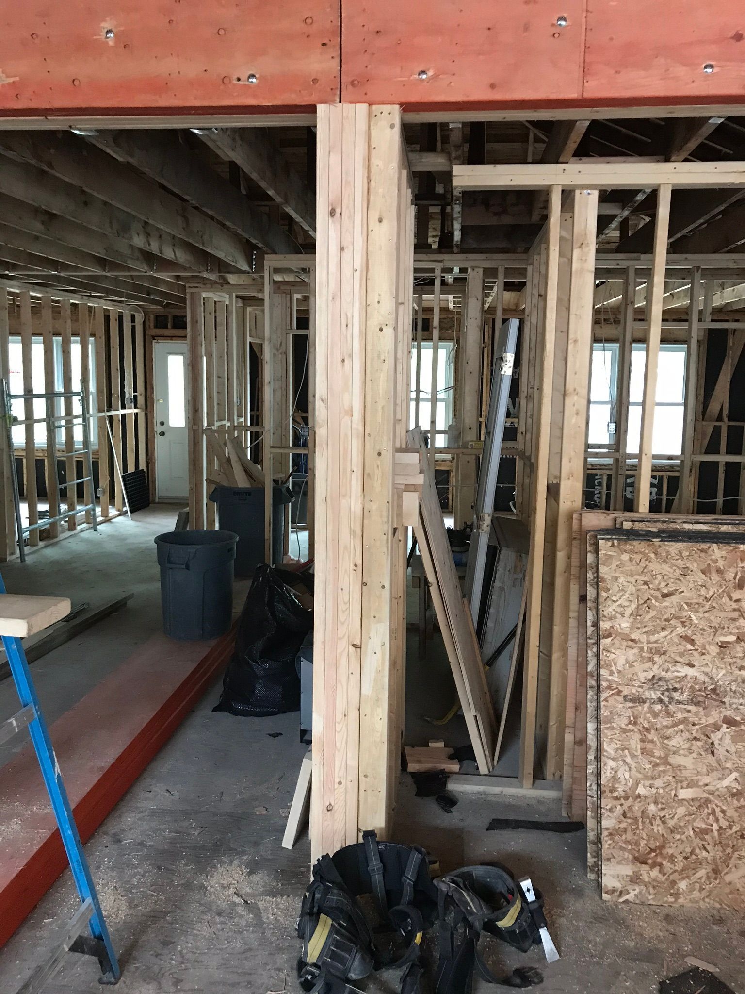 Intérieur d'un bâtiment en construction, montrant la charpente en bois apparente et des pans de murs.