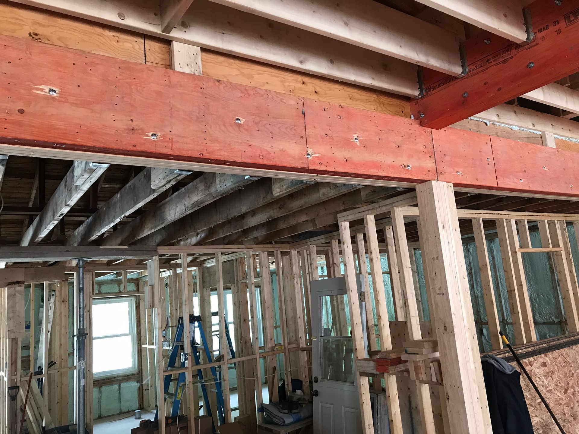 Ossature intérieure d'un bâtiment en construction, avec poutres et montants apparents.