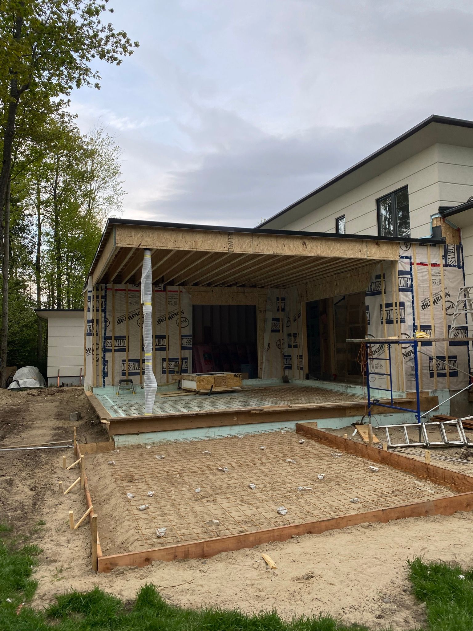 Construction d'une extension de terrasse en bois à ossature apparente, à côté d'une maison à deux étages.