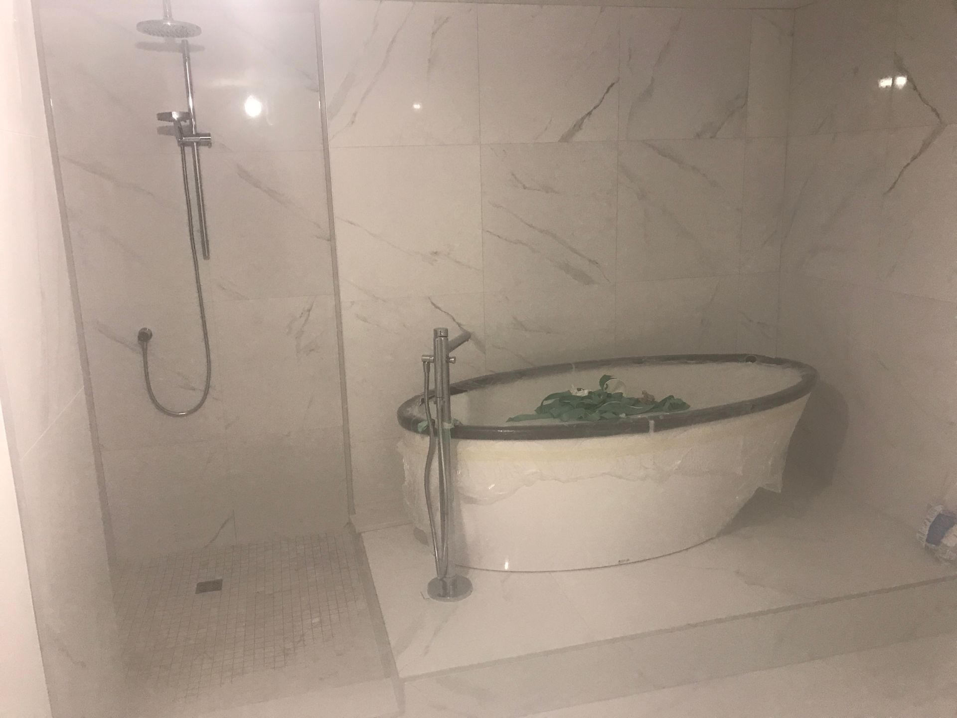 Salle de bains blanche avec baignoire îlot et pommeau de douche.