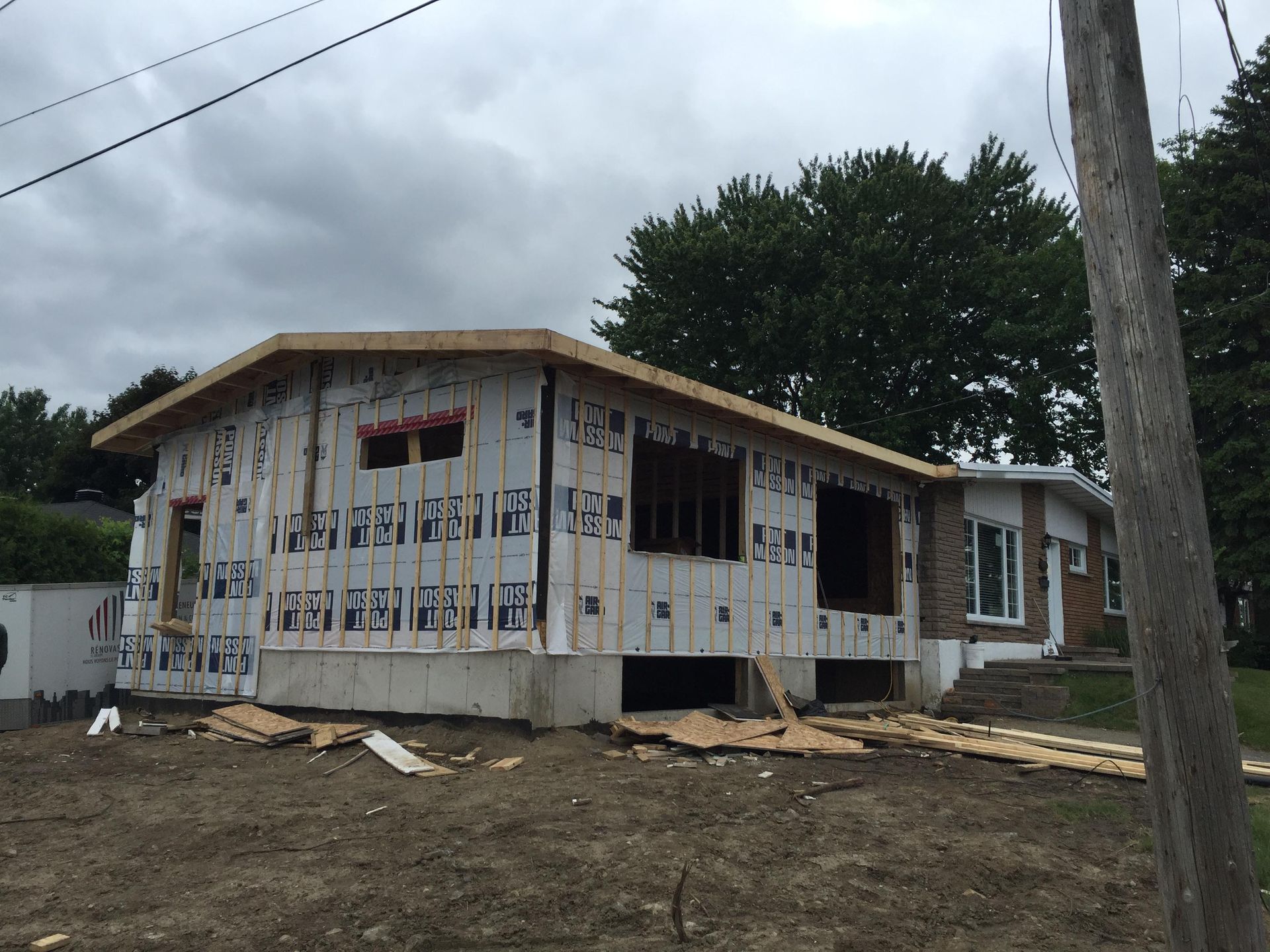 Maison en construction avec charpente et bardage apparents. Travaux extérieurs.