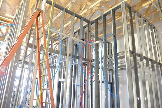 Ossature métallique des cloisons intérieures avec plomberie et câblage électrique installés, en cours de construction.