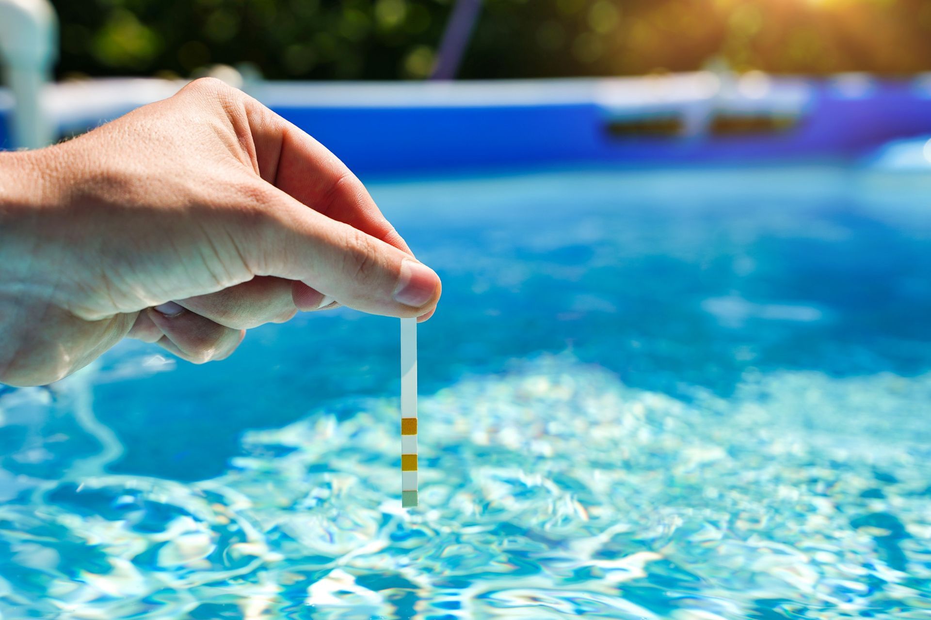 Hand testing pool water with a strip.