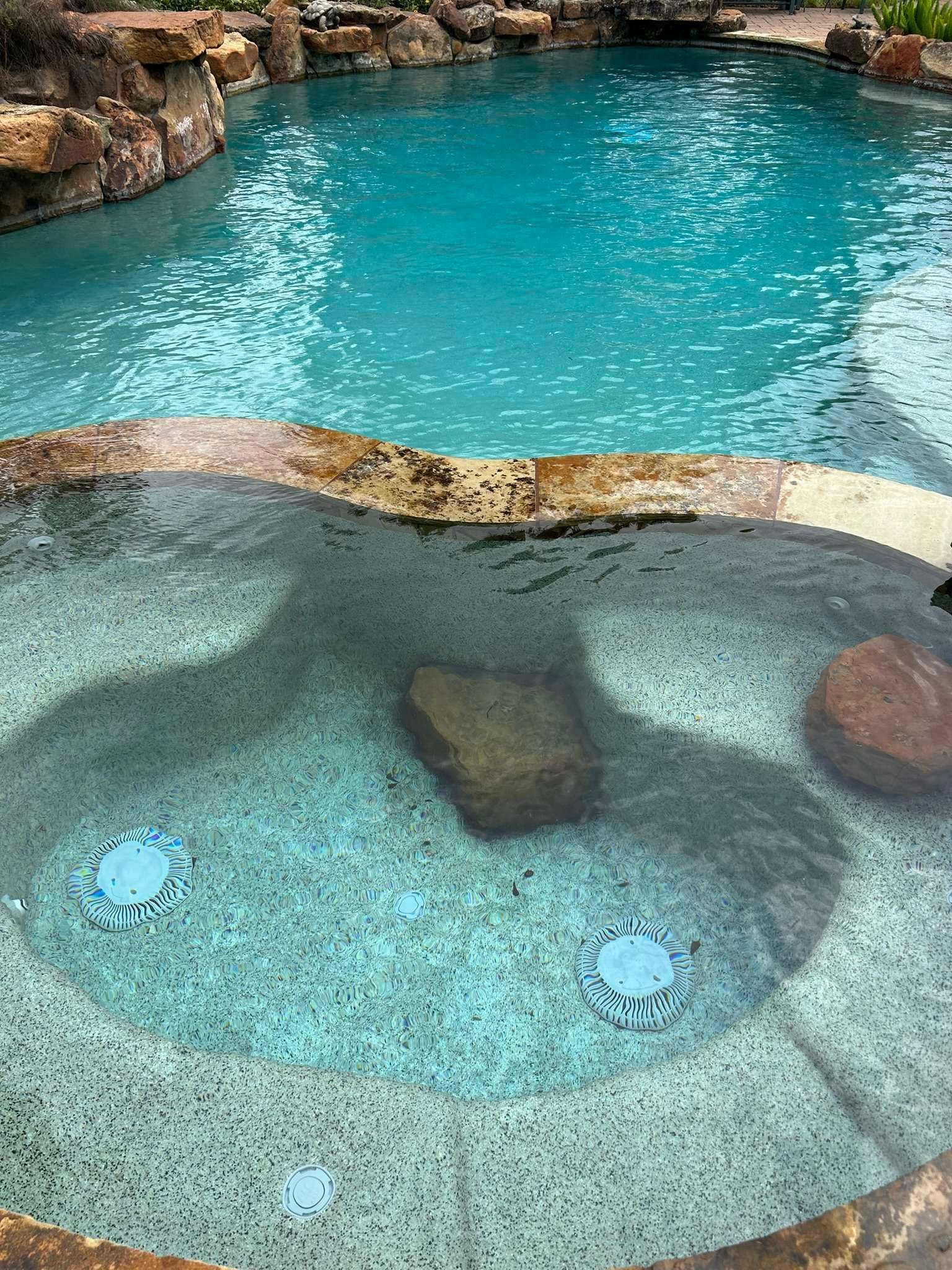 Pool with turquoise water, a connected spa, and rock accents.