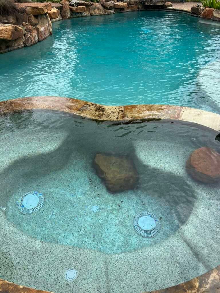 A spa and pool with clear, blue water surrounded by natural rock formations.