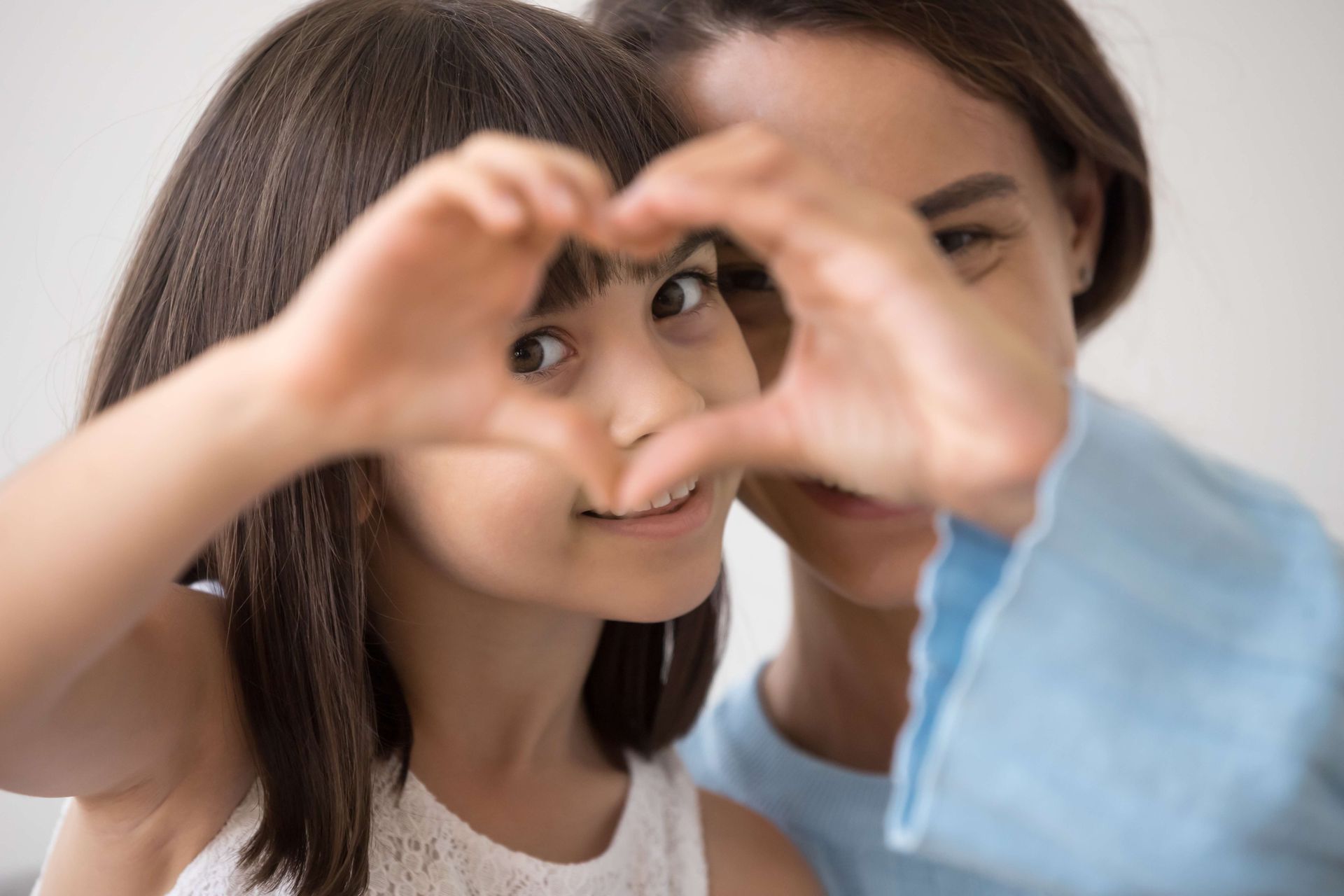 a mother and daughter are making a heart shape with their hands