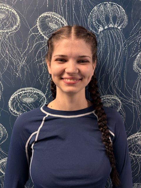 A woman with a nose ring is smiling in front of a wall with jellyfish on it.