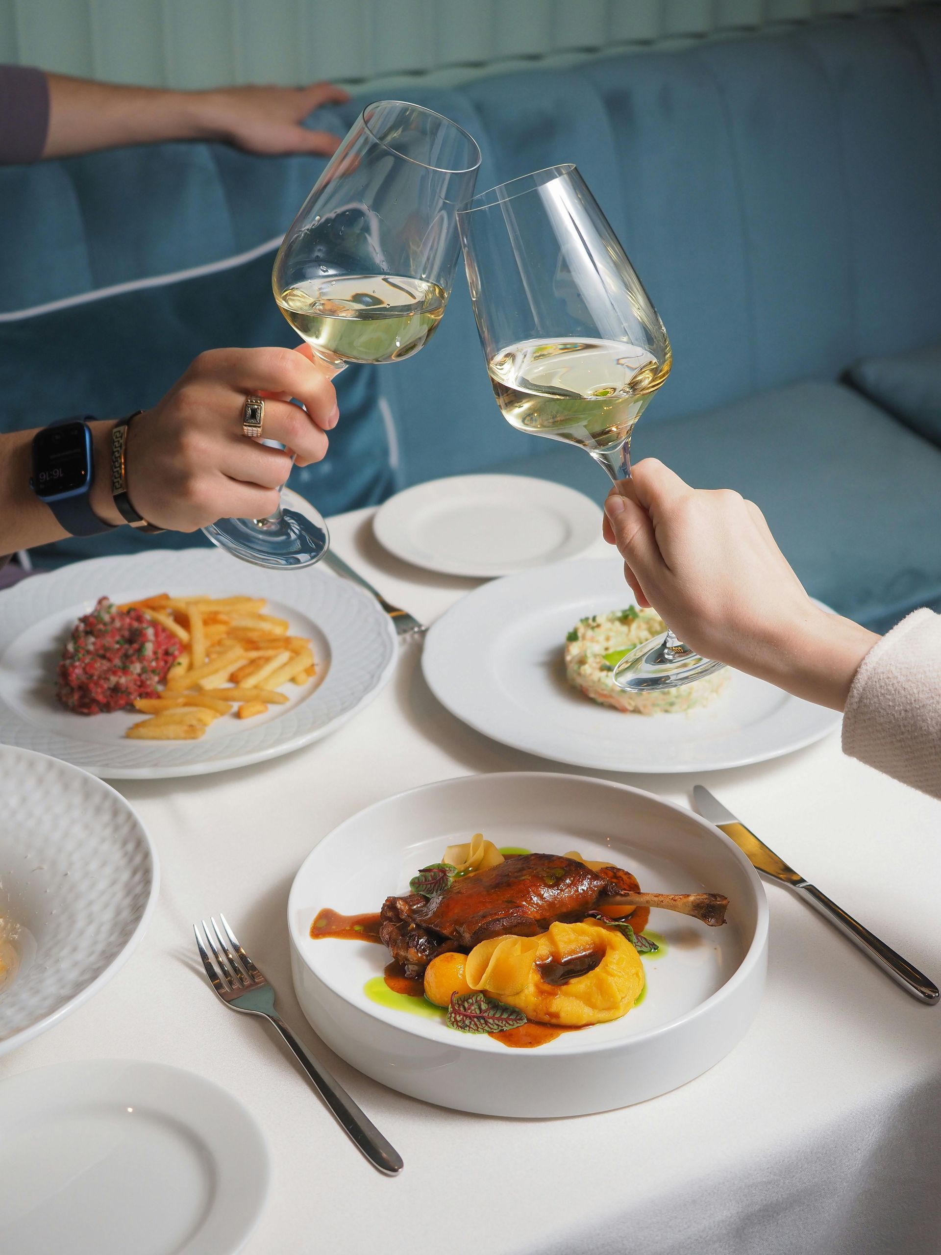 A couple toast their drinks over dinner.