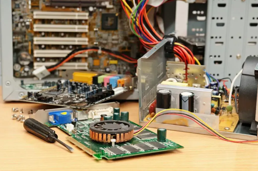 A computer is being repaired on a wooden table.