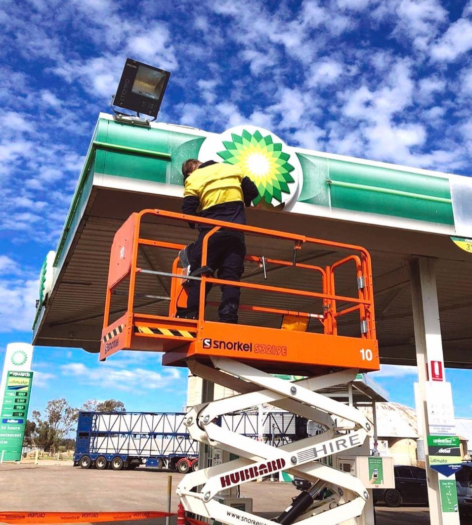 Electrician Replacing Signage Of The Service Station — Electrical Contractors in Tamworth, NSW
