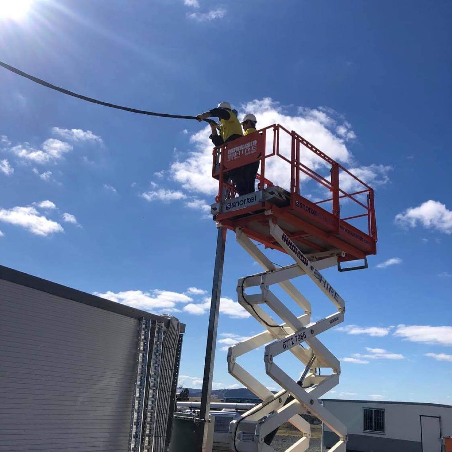 Electricians In A Snorkel Lift Fixing Cables — Electrical Contractors in Inverell, NSW
