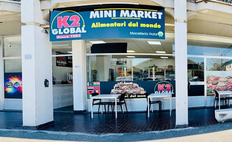 Negozio al dettaglio K2 Global con tavolini all'aperto e insegna blu all'interno di un centro commerciale.