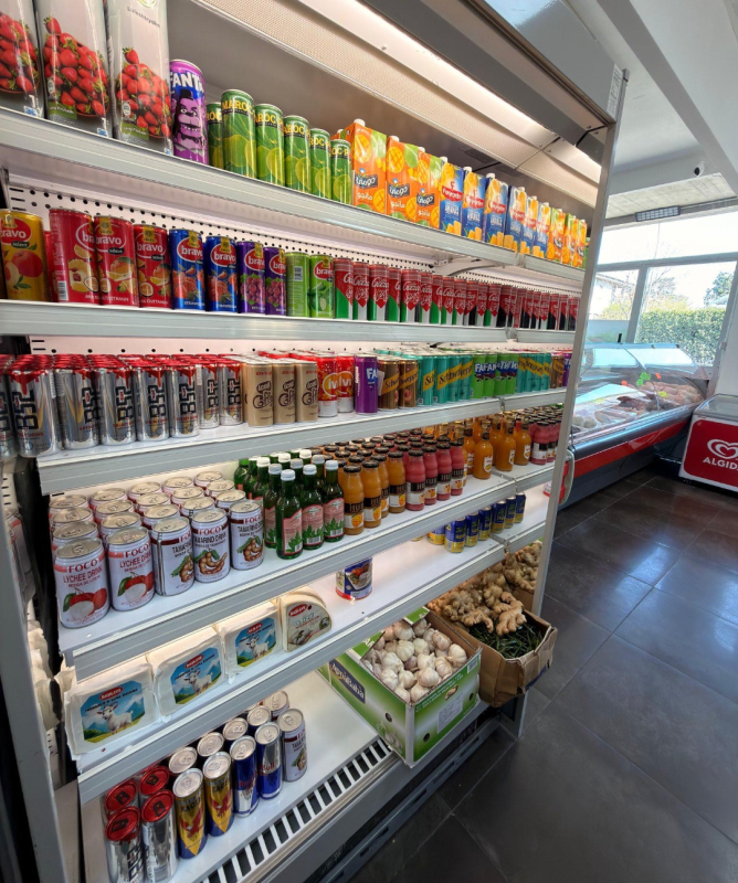 Sistemare un espositore refrigerato per bevande con bottiglie colorate di bibite, succhi di frutta e acqua sugli scaffali.