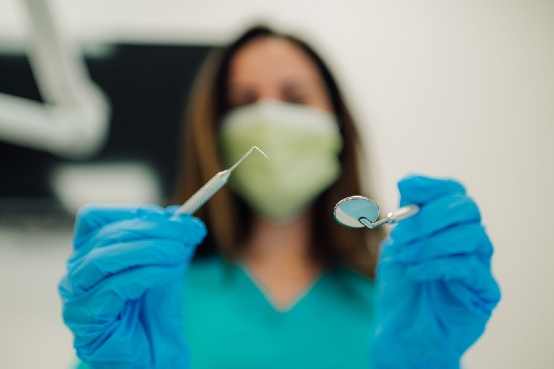 Dentist in mask examining patient's teeth in dental office.