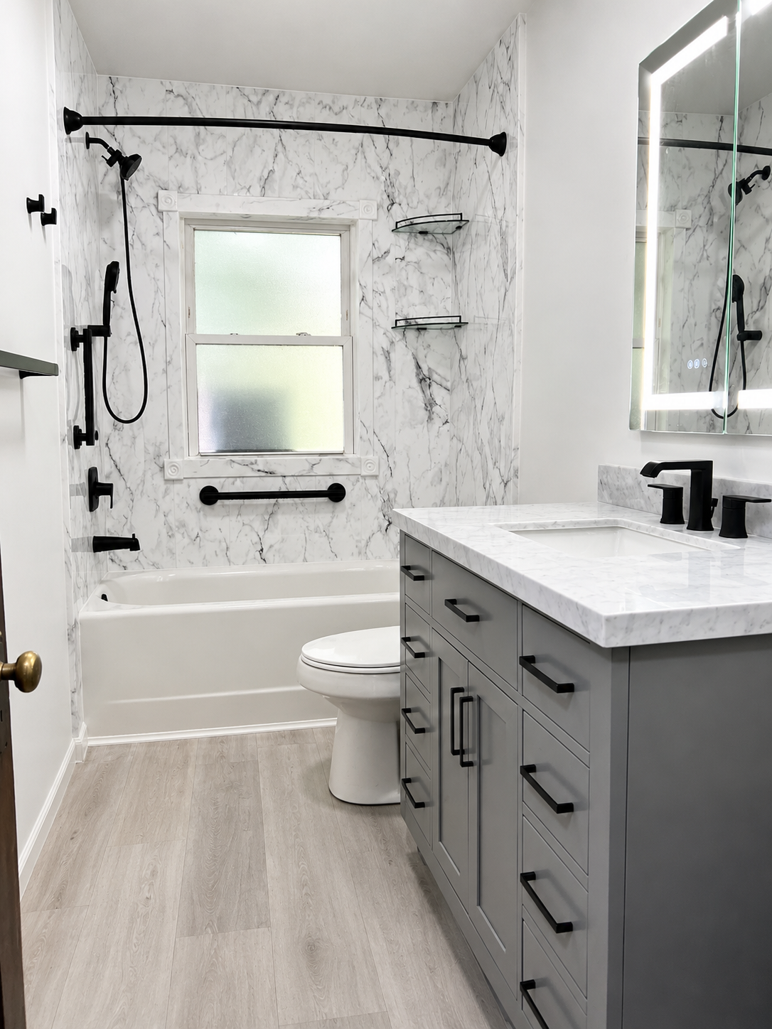 Modern bathroom with marble-look shower, white tub, gray vanity, and bright window
