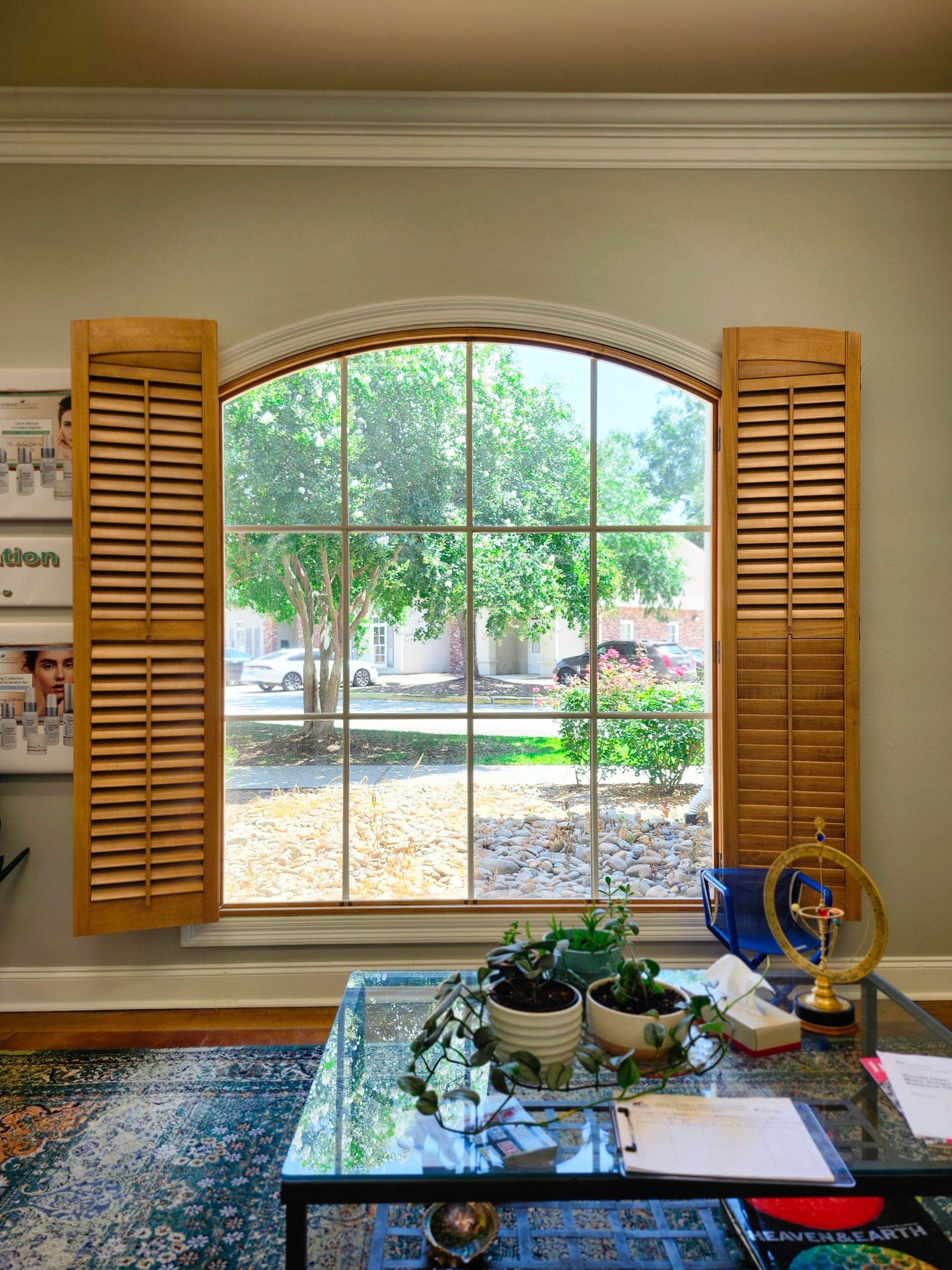 A living room with a large window and wooden shutters.