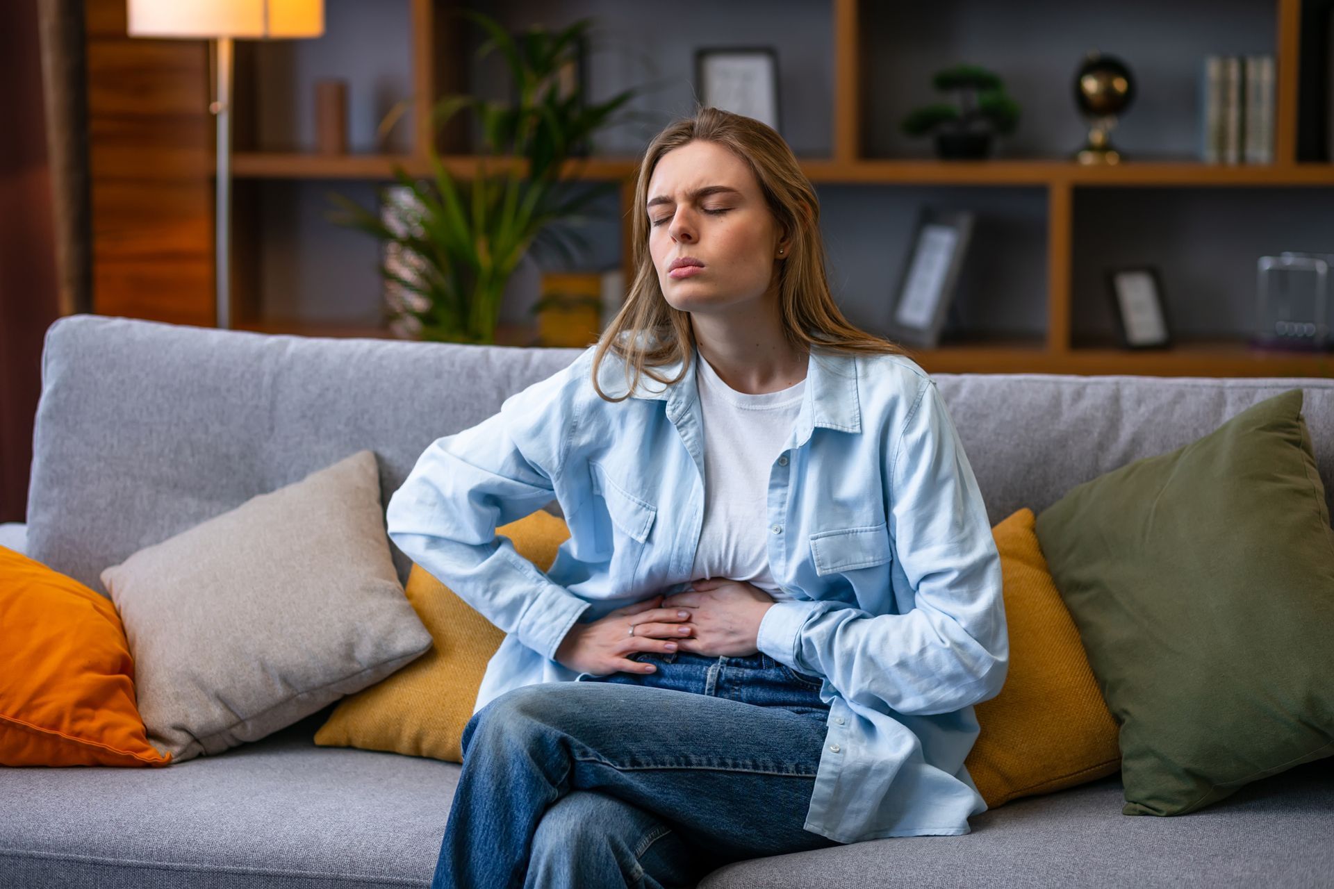 A woman is sitting on a couch with her hands on her stomach