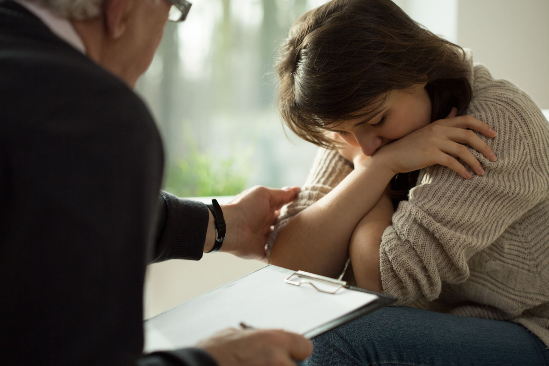 A woman is sitting in front of a man holding a clipboard