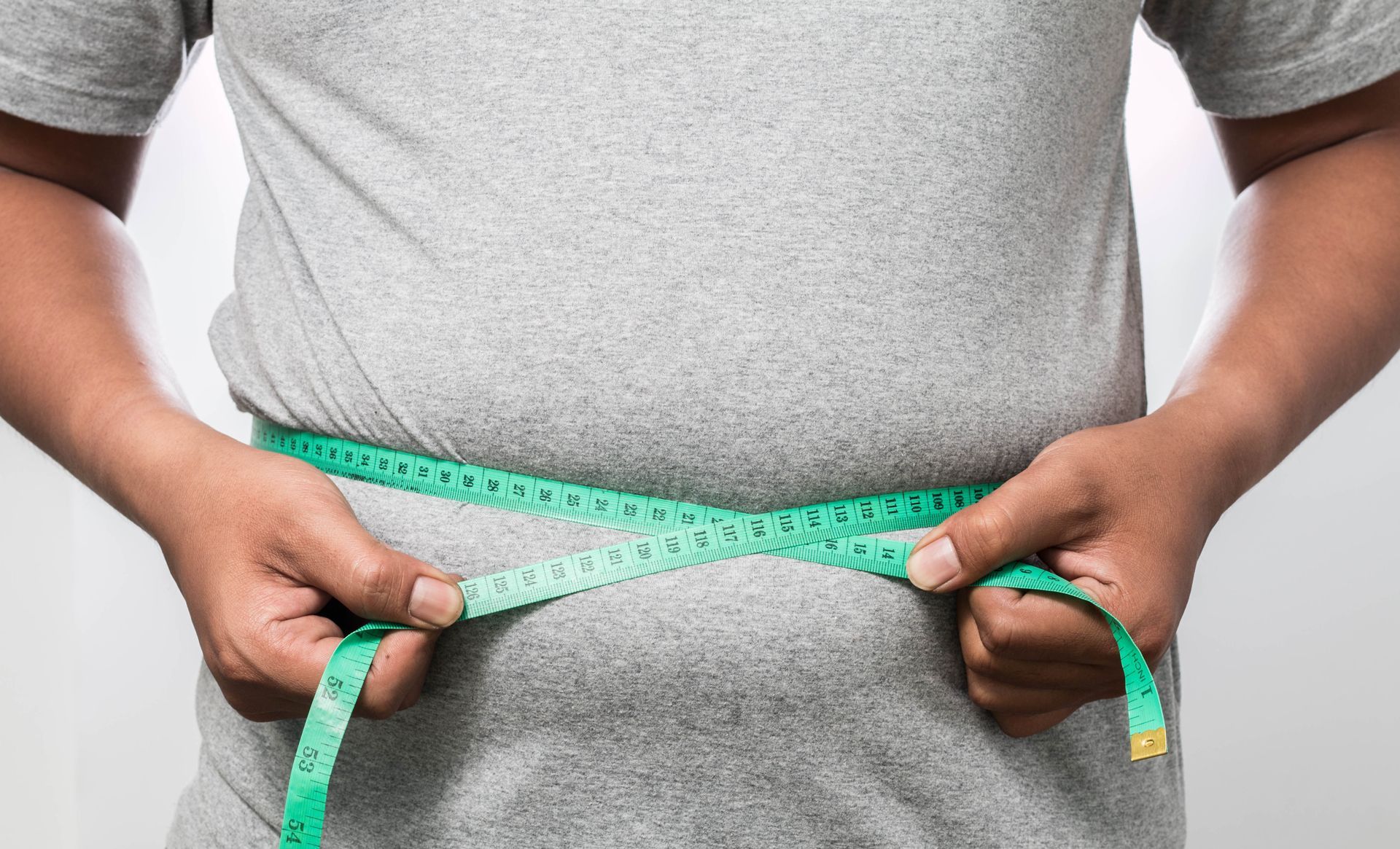 A man is measuring his waist with a tape measure
