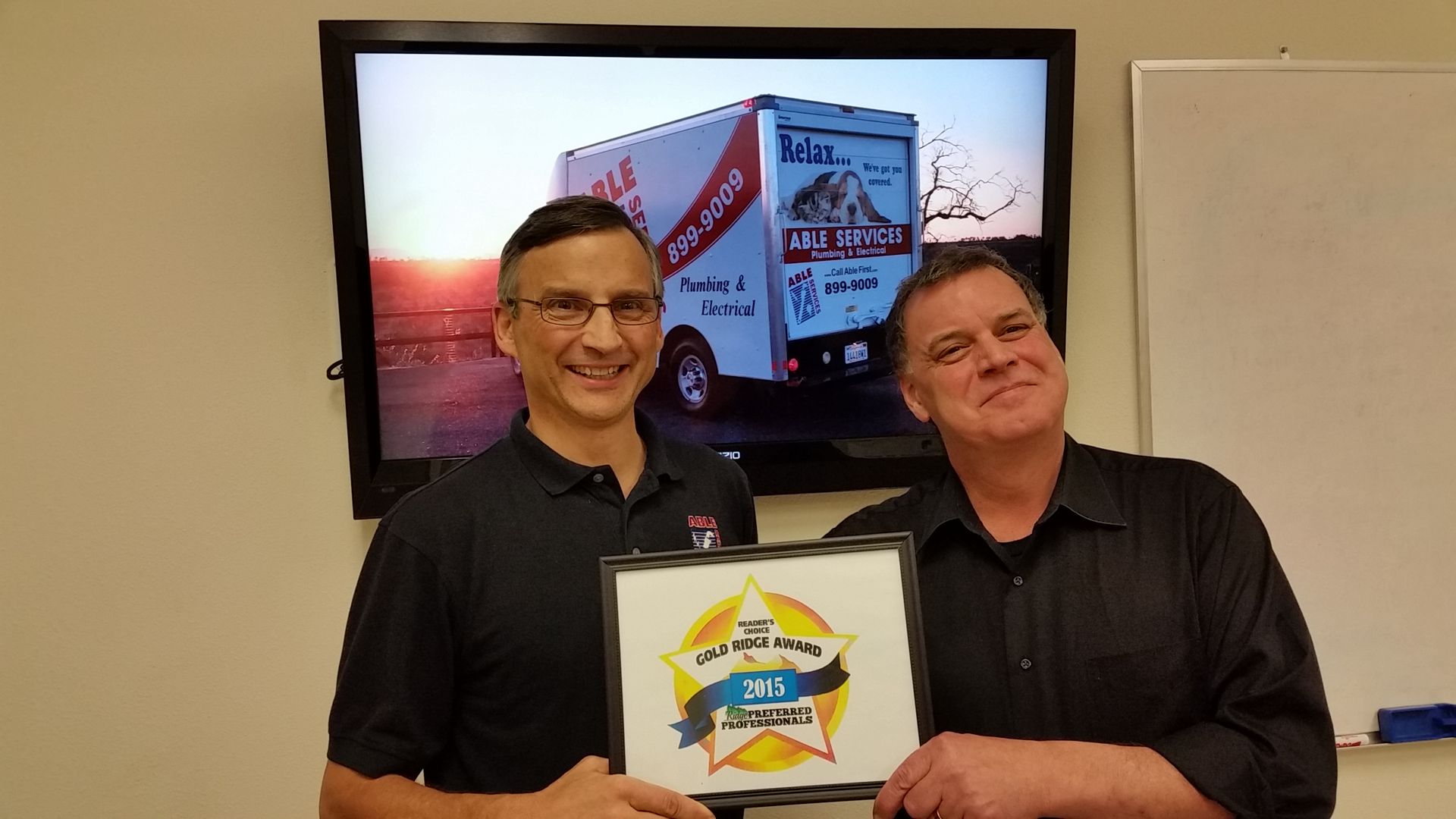 Two men are holding a sign in front of a moving truck.