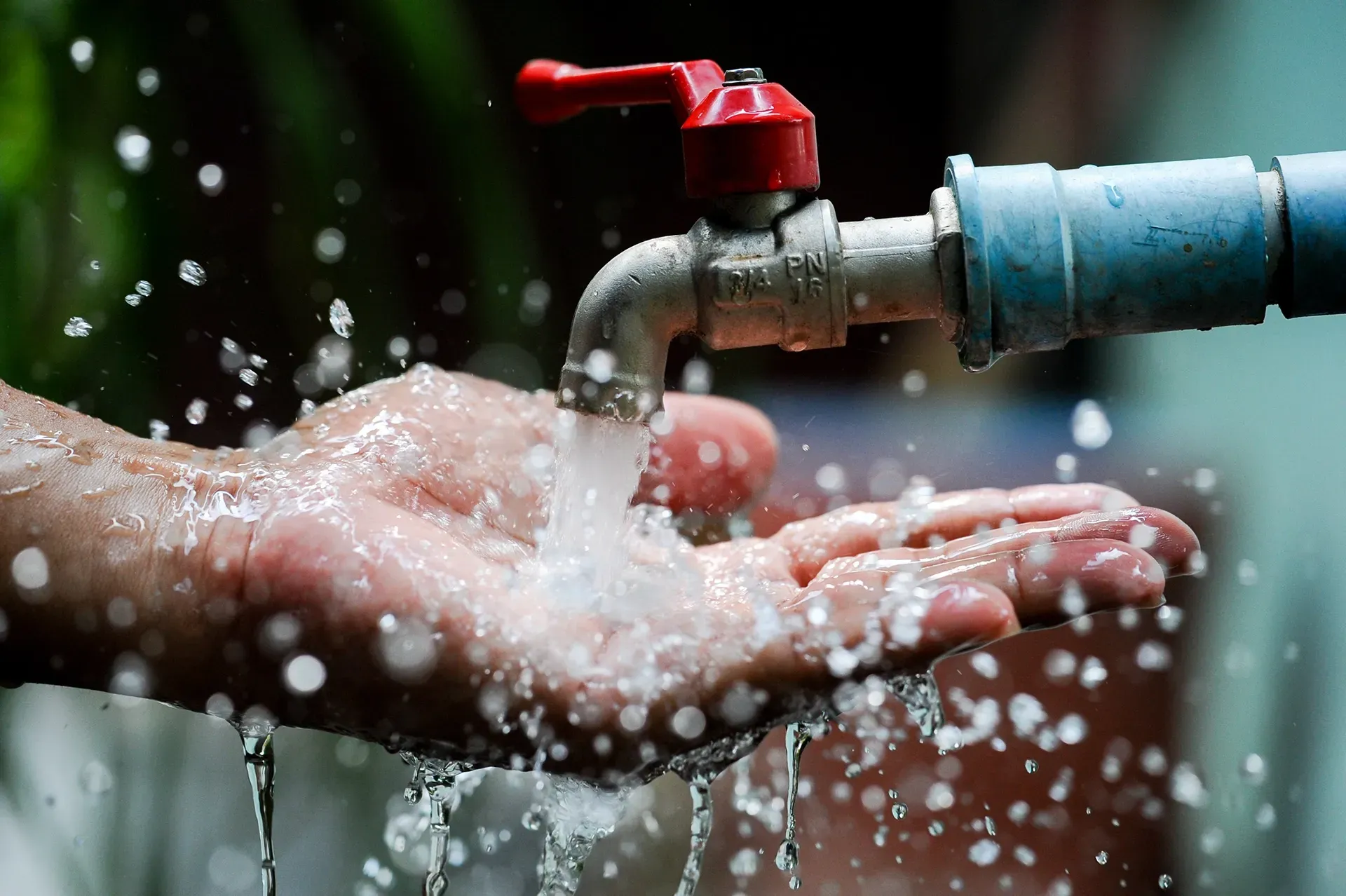 a person is washing their hands under a faucet .