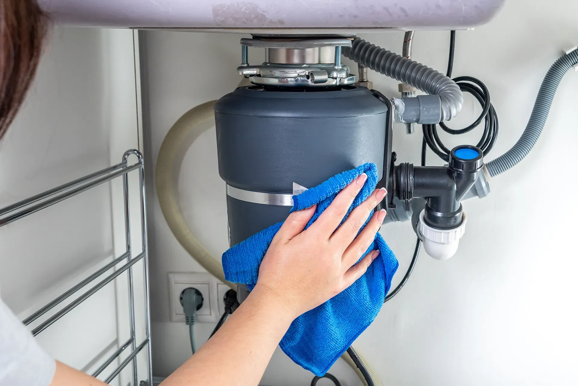 a woman is cleaning a garbage disposal with a blue cloth .