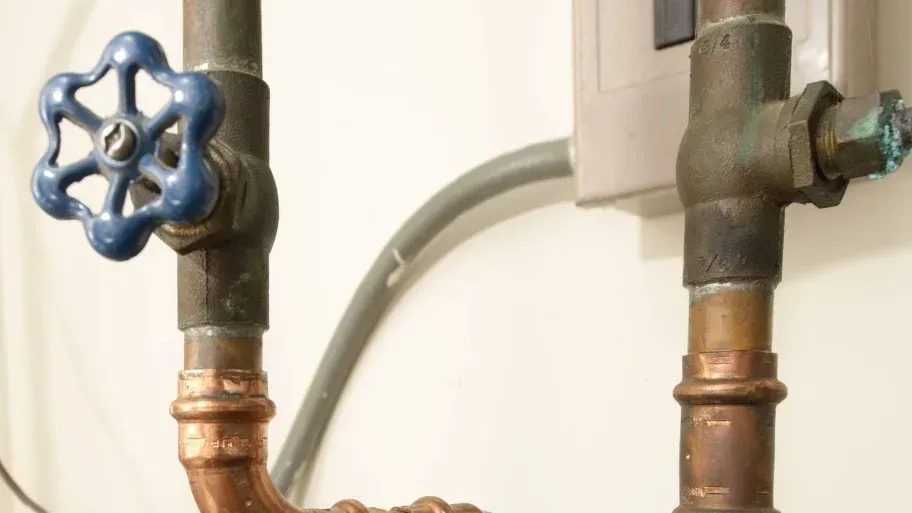 Two copper pipes with blue valves attached to them.